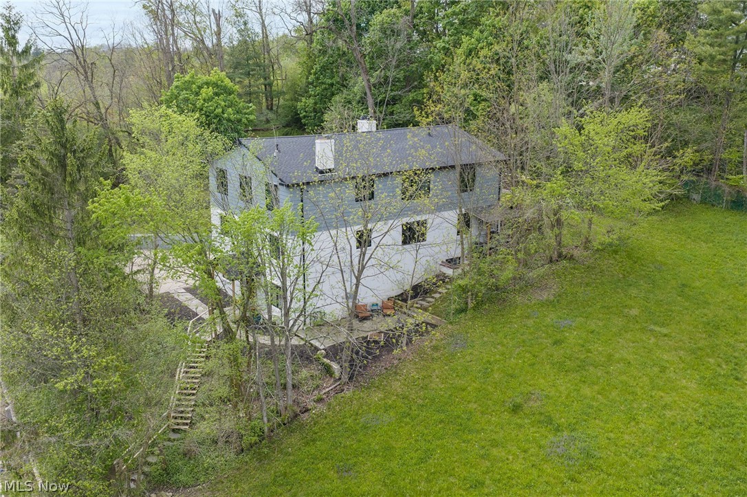 Incredible opportunity on over .41 of an acre property in the heart of Chagrin Falls, just steps from downtown shopping, restaurants, Riverside Park, and the iconic waterfalls. Overlooking the village with a deck, 2 balconies, and stone patio with wooded views, and a 2nd stone patio with views of downtown, this extensively renovated property offers exceptional flexibility as a high-performing income property or a truly one-of-a-kind personal residence within the Chagrin Falls School District. Taken down to the studs and transformed with over $1.8 million in improvements, including $48,000 in new piping from the home to the sewer in 2024, the property is currently configured as a short-term rental with strong income potential estimated at  up to $15,000 per month. An elevator services the home, while a 4-car tandem garage and driveway parking for up to 9 vehicles add remarkable convenience rarely found this close to the village. The open-concept main level is designed for gathering, featuring a spacious family room with stone fireplace and balcony access, dining area with built-in live-edge wood bar, updated eat-in kitchen with stainless steel appliances and center island, plus a guest bedroom, full bath, and a sitting room with patio access that could serve as an additional bedroom. The third-level is highlighted by a vaulted owner’s suite with floor-to-ceiling stone fireplace, private balcony, walk-in closet, and spa-inspired bath with soaking tub and tiled Roman shower. This level also offers 2 additional bedrooms, including one with access to the deck, laundry, and the potential to complete a third kitchen for expanded rental use. The lower level functions as a private suite with its own entrance, living area, kitchen, bedroom, and full bath. INCLUDED are ALL kitchen appliances and washer/dryer.