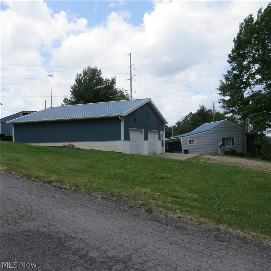 One-Story Home with Nice 32'x32' Detached 2-Car Garage on .833-acre Lot! Auditor's card reports the structure as built in 1860 and basement shows log beam supports. It isn't known currently if the walls are log construction. The floor plan includes nicely updated eat-in kitchen with Aristokraft cabinets, pantry, living room, 2 bedrooms, entry/mud room, and updated bath with walk-in shower. The full walkout-level basement has stairlift for helpful access, laundry hookup, gas furnace with central AC, and updated electrical panel. Home has metal roofing installed along with replacement windows and vinyl siding. A 13x30 screened patio is great for enjoying coffee or family gatherings. The 2008 2-car detached garage has heat, full bath, electric panel with 50-amp exterior plug, etc. Really a nice garage bldg. with block foundation, metal siding and roofing suitable for different uses. There's also an upper metal sided shed located behind the garage suitable for boat or camper storage. Triangular-shaped parcel that lays good and has easy road access. Fruit trees and shade trees with ferns and a level garden area. Great country property with no zoning nor restrictions. All owned minerals transfer with property which produces a small, annual royalty. Annual taxes without the Homestead Reduction are $1064. Call with questions or to view the property.