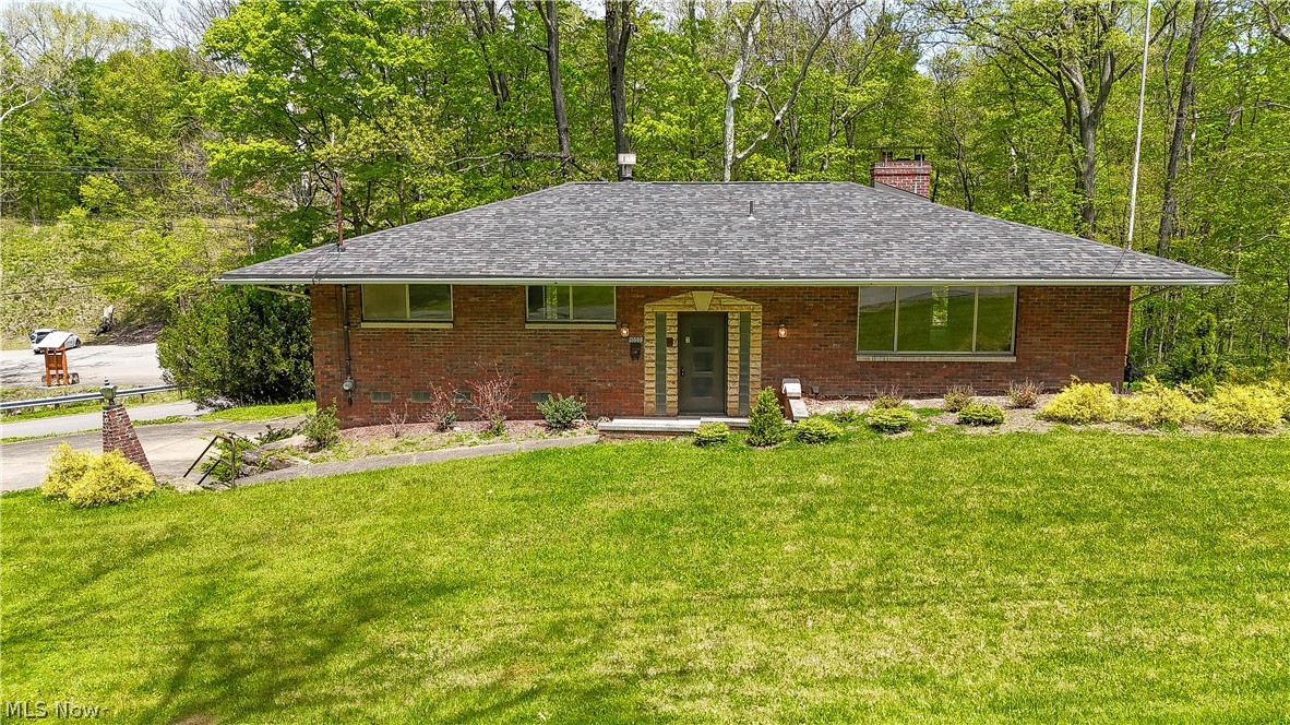 Tucked into a stunning hillside setting near the entrance of Girard Liberty Memorial Park, this one-of-a-kind brick and stone home offers a rare blend of privacy, character, craftsmanship, and natural beauty. Designed with a mid-century modern feel, the home presents as a ranch from the front while opening to a two-level walkout layout in the rear, taking full advantage of the wooded views, stream, tiered landscape, and peaceful outdoor surroundings. Large windows and glass doors throughout the home create a seamless connection between the interior spaces and the incredible backyard setting. Inside, you’ll find spacious rooms, custom millwork, built-in cabinetry, multiple fireplaces, and unique architectural details that are hard to find in today’s homes. The living and dining areas feature beautiful stone fireplace accents, while the lower-level family room is an entertainer’s dream with a custom oval bar, brick and glass block details, bar sink, French doors to the patio, and additional custom cabinetry. The oversized game room offers plenty of space for recreation, and the pool table can remain with the home. The primary suite includes two closets, a private full bath, and access to its own balcony overlooking the property. Additional features include a generous family bath with double sinks and abundant cabinet storage, a large laundry room with exterior access, and a half bath already plumbed for a future shower. Recent updates include a newer roof, fresh paint and flooring throughout, LED lighting, and an all-new electrical service with updated GFCI outlets. Outside, the property is truly special, with extensive stonework, a mosaic-style rear patio, a spiral staircase from the dining/kitchen area to the backyard, mature trees, and beautifully developed outdoor spaces across nearly half an acre. A truly unique home offering privacy, charm, craftsmanship, and an incredible natural setting.