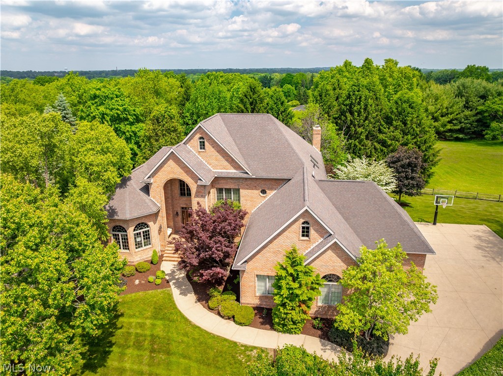 Situated on one of the highest points in Stark County within prestigious Monticello, this extraordinary custom-built Bancroft estate offers a blend of luxury, craftsmanship, and timeless elegance. Perfectly positioned on over a half-acre desirable lot with breathtaking surroundings, this one-of-a-kind home showcases stunning brick curb appeal and an unforgettable presence. Step through the grand foyer into a remarkable interior highlighted by soaring vaulted ceilings, dramatic floor-to-ceiling windows, and beautifully designed living spaces ideal for both entertaining and everyday living. The impressive family room is filled with natural light and anchored by a fireplace, seamlessly opening to the heart of the home, an expansive chef’s kitchen featuring double ovens, gas burners, a large center island, abundant cabinetry, and a spacious dinette with an adjoining wet bar area. A sophisticated first-floor office with custom built-in cabinetry creates the perfect executive workspace. The luxurious first-floor owner’s suite serves as a private retreat with travertine tile flooring, a spacious bedroom leading to the back deck, a spa-like bath with double vanities, and separate his-and-her walk-in closets. An additional first-floor guest bedroom with a private full bathroom offers ideal accommodations for guests or multigenerational living. Upstairs, three generously sized bedrooms each feature their own adjoining bathrooms. The fully finished walkout lower level expands the living space with a full kitchen, bedroom, full bathroom, daylight windows, and ample storage. Outside, enjoy views from the expansive Trex deck or relax beneath the covered patio surrounded by beautiful hardscaping and a serene backyard setting. A three-car garage with basement access completes this exceptional property. With six bedrooms, six full baths, one half bath, and dual laundry areas, this Monticello residence redefines luxury living with access to a clubhouse, pool, and exercise facility.