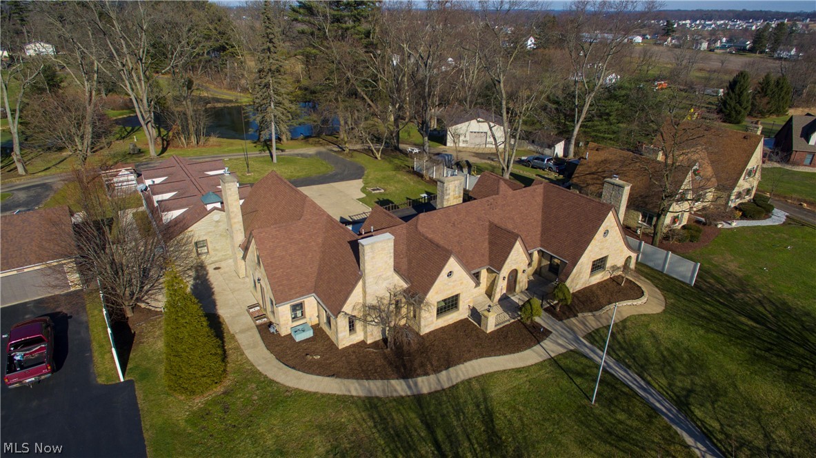Astonishing 5 bedroom 4,700 sqft sandstone Tudor home filled with modern amenities and delightful extras! Situated on an acre with water views, a circle drive and a heated 3-car attached garage - the third bay offers a 9-foot door and spigots for washing your car! Set up for entertaining, back-to-back gourmet kitchens doubles your cooking potential! Double ovens, 2 dishwashers, 2 sinks - this layout will change the way you do holidays! Plus enjoy the fireplace, granite countertops, stone backsplash, wine cooler, walk-in pantry and updated cabinetry. Enormous dining room perfect for hosting as well as ample bar seating. The living room boasts a fireplace with a woodburner insert and a grand spiral staircase up to a set of glass French doors. These open to a unique flex space with pitched ceilings - the perfect office, playroom and bedroom areas. Here, there's attic access and a glass door to the balcony with water views. The first floor master suite includes a fireplace and a 13x9 walk-