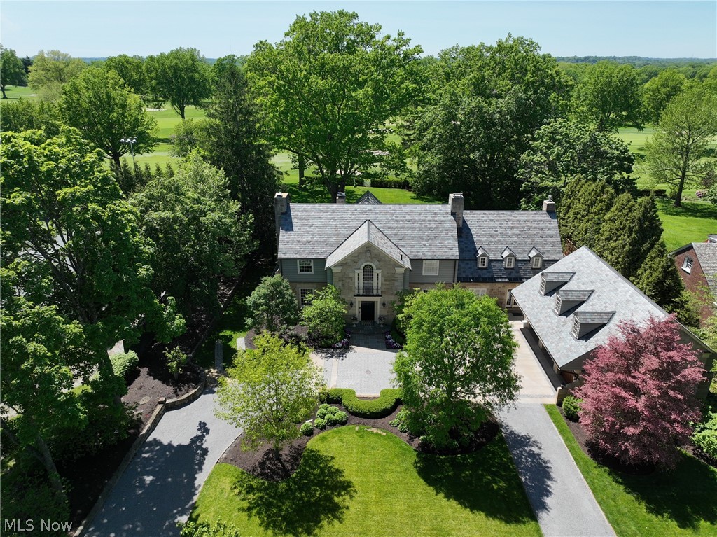 Welcome to this timeless 5-bedroom, 5 full & 3 half bath striated Sandstone Colonial ideally situated on one of West Akron’s most iconic settings, adjacent to the historic Portage Country Club Tennis & Aquatics Center and overlooking the 18th fairway of the golf course. Originally established in 1928 by Gus O'Neil & constructed 8 years after Stan Hywet was finished, this extraordinary estate has been exquisitely renovated while thoughtfully preserving its rich architectural character and historic charm. Exceptional details include the O’Neil family insignia, Fleur-de-lis accents woven throughout the home & grounds, Carolina gas lanterns, slate roof, stone curbs transported from Cleveland & granite pavers from a local Rubber Company, and more. Guests are welcomed through the original Tiger Maple front door into elegant living spaces filled with timeless craftsmanship and warmth. The stunning screened-in porch opens seamlessly to the newly redone bluestone patio featuring a beautiful lion fountain and breathtaking sunset views. Take in the 95-year-old beech & oak trees, as well as limelight hydrangeas, Eastern redbuds, alliums, and more throughout the hallowed gated grounds.  The original garage was masterfully transformed in 2012 into a truly one-of-a-kind chef’s kitchen featuring a Lacanche range, custom knotty hickory Mullet cabinetry, Zebra Walnut island countertop, and soapstone perimeter counters. The luxurious owner’s suite, plus 3 additional bedrooms, all with en-suite baths, complete the 2nd floor. The third floor features a living suite complete w/5th BD & full BA. Additional living space is in the LL complete w/family room, rec rm, workout rm, wine cellar and half BA. Space above the garage is plumbed for the addition of a private guest suite. A rare opportunity to own a landmark West Akron estate where historic elegance and thoughtful restoration come together in an unmatched country club setting.