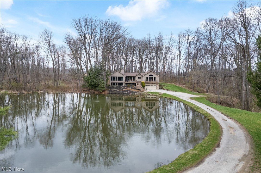 Discover unparalleled privacy at 4453 Blachleyville Rd in Wooster, OH, a 3,581-square-foot sanctuary nestled nearly a half-mile off the public road on 8.60 wooded acres. A lengthy driveway welcomes you, wrapping around a serene private pond before leading directly to a large garage and utility space, the main entry, and steps up to an inviting front deck. Inside, large windows flood the home with natural light, highlighting the soaring cathedral ceilings in the spacious living and dining room, which centers around a cozy fireplace. The expansive U-shaped kitchen is a home chef's dream, boasting gleaming granite countertops and an incredible amount of counter space. You can enjoy the sights and sounds of nature from the relaxing screened-in porch, while everyday convenience is maximized by a main-level laundry room and attached mudroom that features practical side door access, a utility sink, dedicated counter space, and ample cabinet storage. The picturesque, wooded surroundings teem with an abundance of deer and wild turkeys, making it an idyllic spot for hunting right on your own property. Complete with a cleared space perfectly suited for building an additional garage or pavilion, as well as the rare added benefit of a shared gas well, this secluded haven offers the ultimate blend of peaceful rural living and modern comfort. (Please don’t enter driveway without an appointment.)