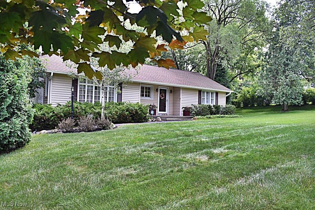 Charming, adorable, immaculate all describe this wonderful home...AND all on a 1.15 Acre lot! Enter into the large open Foyer with hardwood flooring and unique curved wall and you'll have a view of the over-sized Living Room with hardwood floors, wood burning Fireplace with blower / insert for those cozy evenings at home and large front window that allows so much natural light and views.  Living Room opens to the dining area also with hardwood floors.  Dining Room has access to the coziest Sun Porch area with views from every window!  The Dining Room also opens to the Kitchen with beautiful breakfast bar, natural wood cabinetry and back door that leads to a terrific deck, with retractable awning and those wonderful, wooded views of the back yard...imagine having your morning coffee and enjoying the private views that surround you!  All appliances will stay!  Two Bedrooms and a Full Bath will complete this level. Full Basement has a workshop / utility area, large pantry and a huge Recreation Room area with laminate flooring.  There's also a half bath with separate shower area in the laundry room.  Access to the one car garage is on this level. A storage shed offers even more storage. This home has it all!  Close to freeways yet minutes away from the MetroParks, Shawnee Golf course, shopping and entertainment. If that's not enough, Walton Hills Lake Club is available for membership.