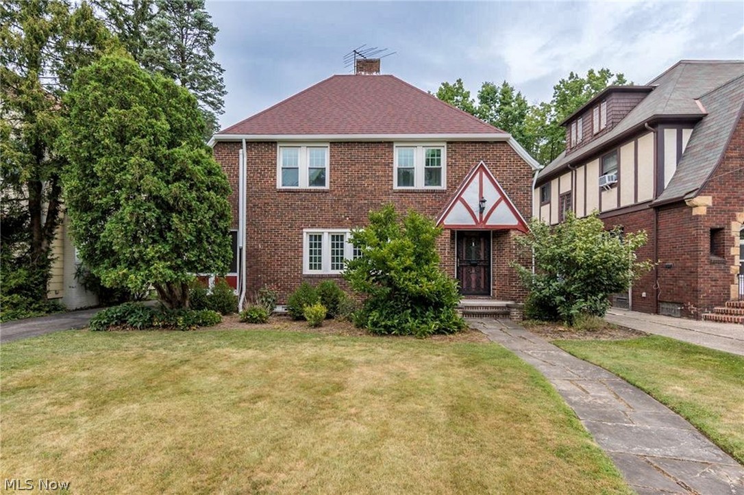 Welcome to this charming brick-and-Tudor Revival Colonial nestled on a quiet, tree-lined street. Through the original front door, you are greeted by an elegant staircase and an inviting archway leading to the spacious living room, where a dramatic wall of windows fills the space with natural light. A beautiful fireplace serves as the room's focal point, while an enclosed porch just off the living room offers the perfect place to spend a quiet afternoon with a good book. Continue through the home to the formal dining room, highlighted by leaded-glass windows, and a cozy office featuring built-in bookcases. The kitchen is light, bright, and beautifully updated with stunning light stone countertops, a tile backsplash, stainless steel appliances, and abundant storage. A convenient powder room for guests completes the main level. Outside, you'll find a four-car garage with plenty of space for vehicles, hobbies, or additional storage. Beyond the garage, a whimsical stone archway leads to the expansive backyard, complete with stone-walled garden beds that create a picturesque outdoor retreat. Upstairs, the second floor offers four bedrooms, including a spacious primary suite with direct access to the full hall bath. The finished lower level features a large rec room with a wet bar and an additional full bath, making it an incredibly versatile space that can easily serve as a second family room, game room, home gym, or entertainment area. All of this is conveniently located just minutes from shopping, dining, entertainment, hospitals, and universities.