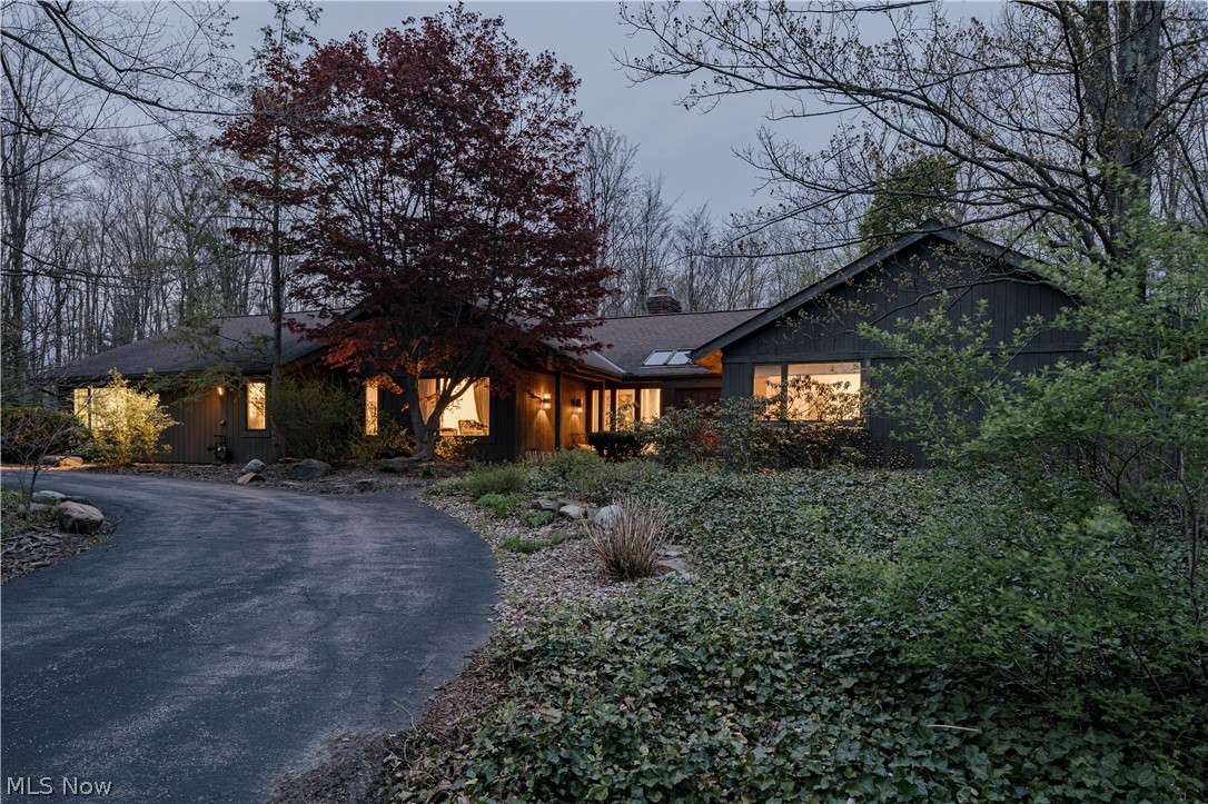 Set on a quiet cul-de-sac street, this expansive modern ranch offers refined living with architectural detail, all in a private setting. A winding driveway leads to an impressive front entrance with stunning double doors. The entry opens into a dramatic living room with a vaulted ceiling and gleaming wood floors. Expansive windows fill the space with natural light. A sleek two-sided fireplace and sliding doors enhance the design and provide access to the outdoors. The adjacent eat-in kitchen has been tastefully renovated and designed for both style and function. It features a spacious dining area with a brick fireplace, granite countertops, a large center island, stainless steel appliances, tile backsplash, and updated wood cabinets. A gleaming  sunroom off the kitchen offers the perfect setting for morning coffee or an evening wind down with walls of windows and natural light. A formal dining room offers a beautiful setting for larger dinner parties.  While the dining area off of the kitchen provides a more casual setting by the fire. A first  floor laundry, a mudroom and a conveniently located half bath for guests complete the main living spaces. Tucked away, the primary suite serves as a true retreat, featuring a spacious bedroom, two walk-in closets, and a well designed ensuite bath with a custom walk- in shower and double vanity. The additional bedrooms are thoughtfully positioned nearby and share a full bath. To complete this stunning home is the lush private setting with botanicals that shine. Enjoy the warmer evenings with sunsets on the deck or patio and the gardens that accent this impeccable estate!
