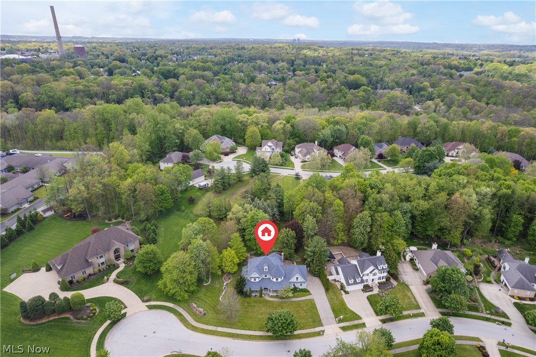 Tucked away on a quiet cul-de-sac, this extraordinary Victorian-inspired home blends timeless craftsmanship with modern comfort on a beautifully landscaped 3/4-acre wooded lot. The desirable lot-and-a-half setting provides exceptional privacy and green space, ensuring no homes can be built directly between you and the neighboring properties. From the cobblestone driveway and inviting front porch to the private backyard, every detail has been thoughtfully designed to create a one-of-a-kind retreat. Inside, you’ll find incredible custom woodworking, intricate built-ins, and stunning wood flooring throughout. The impressive foyer opens to a spacious, light-filled floor plan featuring a formal dining room, elegant front sitting room, and a warm living area anchored by a custom gas fireplace. The eat-in kitchen is both functional and beautiful, offering an oversized pantry, abundant cabinetry, and seamless flow for entertaining. Upstairs, the luxurious owner’s suite feels like a private sanctuary with dual sinks, soaking tub, and massive walk-in closet. Two bedrooms share a Jack-and-Jill walk-in closet and full bath, while an additional oversized bonus room offers flexibility as a fourth bedroom, office, or rec space. A finished basement with a family room and half bath adds even more room to spread out. Surrounded by nature near Cuyahoga Valley National Park and Blossom Music Center, this exceptional home offers easy access to both Akron and Cleveland while feeling worlds away.