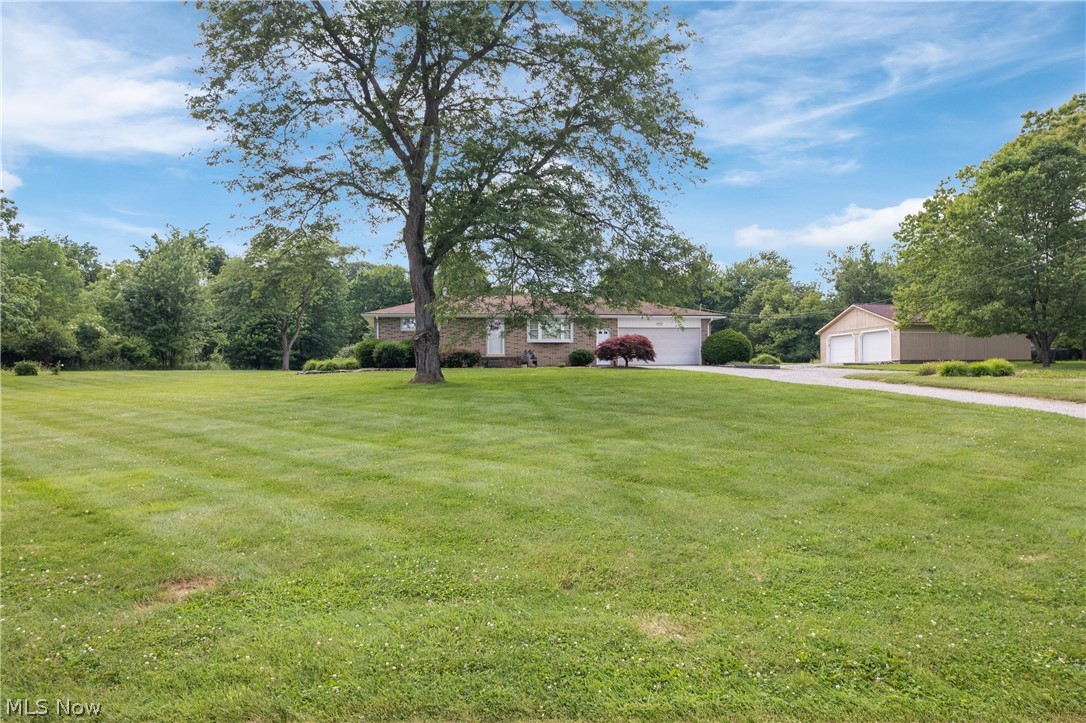 Rare find, sprawling property featuring over five acres of flat land in NW Massillon.  Charming brick ranch featuring 2 bedrooms 1 bath, with spacious living room, and basement could easily be finished to offer additional living space. Upon entering you are greeted with tons of natural light, and beautiful original hardwood floors. Home has been meticulously cared for over the years, and is in pristine condition.  There is a tiered deck off the dining area, opening up to acreage and full of quiet nature.  Deer are plentiful, along with other wildlife and plenty of scenic views. There is a quiet, peacefulness to this property that is something you must experience to understand! Home also features two large outbuildings, tons of extra parking, and more! Updates include roof on outbuilding, hot water tank (2024), and nature stone flooring in attached garage. Set up your private showing today.