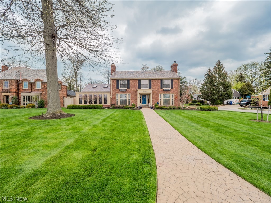 This stunning brick center-hall colonial is the definition of classic residential architecture. Built by the Selby Construction Co., Selby was known for traditional design, lasting craftsmanship, and unique locations, including homes along Lakewood's lakefront and this beautiful example overlooking the Metroparks. Thru the front door is a grand, welcoming two-story foyer with chandelier wrapped by an exquisite staircase. A large living room with fireplace is to east, and west is the dining room. Each is bathed in light shining thru floor-to-ceiling windows. Attention to detail is immediately evident. Hardwood floors, wood trim, crown moldings, are unique, lovely features. Thru the dining room or directly off the foyer is the kitchen which is updated while maintaining its original charm, like a cozy window seat. A hallway leads to the back door and another half bath. A wonderful sunroom facing the river valley is next to the dining room. The basement is half finished with wood paneling,
