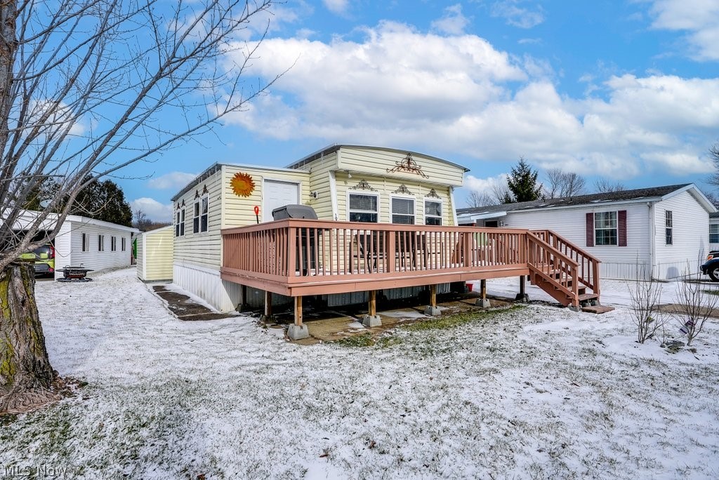 Bright and inviting, this well-maintained and cheerful 2 Bedroom / 1 Bath home in Streetsboro's Camelot Village will delight you with its welcoming and open floorplan and warm wood paneling. You will fall in love with the striking Stone Wood-burning Fireplace that is the perfect centerpiece for entertaining or taking the chill off on a winter day. A sizeable addition creates a spacious and open living, dining and kitchen space that is bathed in natural light by an abundance of easy care tilt-in windows . All Appliances are included in the kitchen with its plentiful cabinets and counter space with bar seating. Both bedrooms have ample closet space, while the primary bedroom includes a built in dresser and dressing table. The full bathroom has a tub/shower combo and also includes a full size Washer and Dryer. Outdoors is an enjoyable deck and two large sheds for extra storage. Hot water tank, kitchen range, and carpets were replaced in 2021. A/C ~ 4 years. Furnace ~ 12 years. HVAC has be