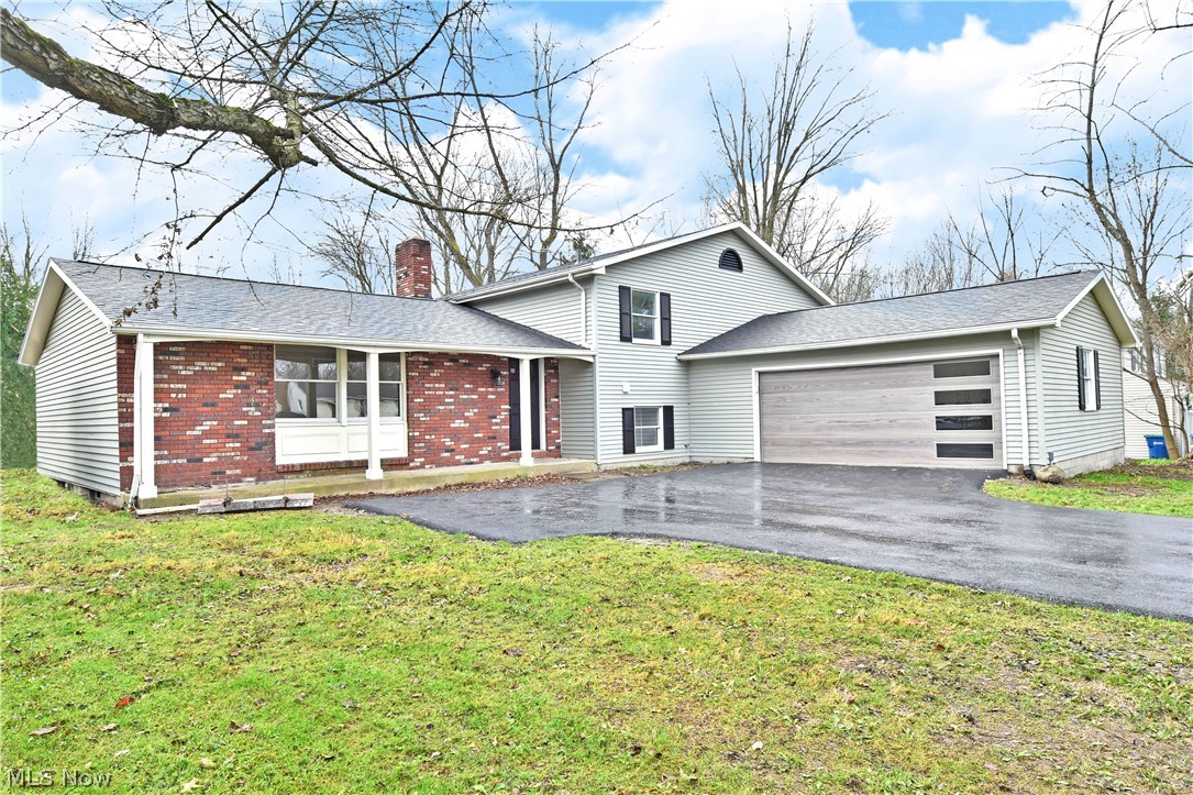 With its expansive, four-bedroom layout and desirable Howland location, this freshly remodeled split level easily stands out from the crowd! First impressions will quickly notice its stylish, custom garage door and brick façade that waits under the covered front patio. Behind, a wooden deck overlooks the back yard. Step inside to be met by an impressive living room that opens to reveal tall ceilings and warm, hardwood style flooring. Formal dining enjoys bespoke lighting and sliding doors for natural light and scenic views. The central kitchen employs gorgeous brickwork paired with dark stained cabinets and modern stainless appliances. Upstairs, an inviting full bath joins the carpeted bedrooms that line the hall. An oversized master suite brings spacious appointments to include a personal vanity, walk-in closet and gorgeous full private bath. At the lower level, a long running family room takes advantage of the fireplace inset mantle. A bonus room breaks away for easy rec space and en