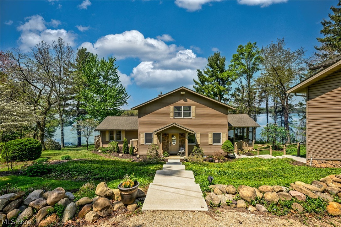 Stunning lake views immediately capture your attention upon entering this exceptional 2,912-square-foot waterfront home on Atwood Lake, set on a beautifully landscaped 0.37-acre lot. Originally an 800-square-foot cottage, the property was thoughtfully expanded in 2007, transforming it into the impressive lakefront retreat it is today. The home offers three bedrooms & three full bathrooms, providing ample space for family & guests to gather & create lasting memories. A private dock, just steps away, offers convenient access to 1,540-acre Atwood Lake—perfect for lake recreation. The open-concept main level is highlighted by a breathtaking great room featuring a dramatic floor-to-ceiling towering wall of glass that frames panoramic lake views & spectacular sunsets. Vaulted solid maple ceilings & flooring, & a wood-burning fireplace enhance the warmth & elegance. The charming kitchen is equipped with granite countertops, a breakfast bar & all-new appliances. The spacious primary bedroom also enjoys serene lake views & includes private access to the main floor bathroom, along with a distinctive fireplace relocated from our nation's White House. Outdoor living is equally impressive, with a screened-in porch off the great room & a ground-level patio, both perfectly positioned to take in the scenic lake views. A convenient main floor laundry room completes this level. A generous loft—currently used as a bedroom—features its own full bathroom, offering additional flexible living space. The lower walk-out level includes a large family room, third bedroom, full second kitchen, and a third full bathroom, all with continued access to the home’s remarkable lake views. A 24x36 detached garage accommodates two vehicles & includes a dedicated workshop area, along with additional space suitable for storage or a hobby room. New concrete walkways & steps connect the garage & parking area, which provides ample space for guests & gatherings. MWCD leased lot rate for 2026 is $6,215.