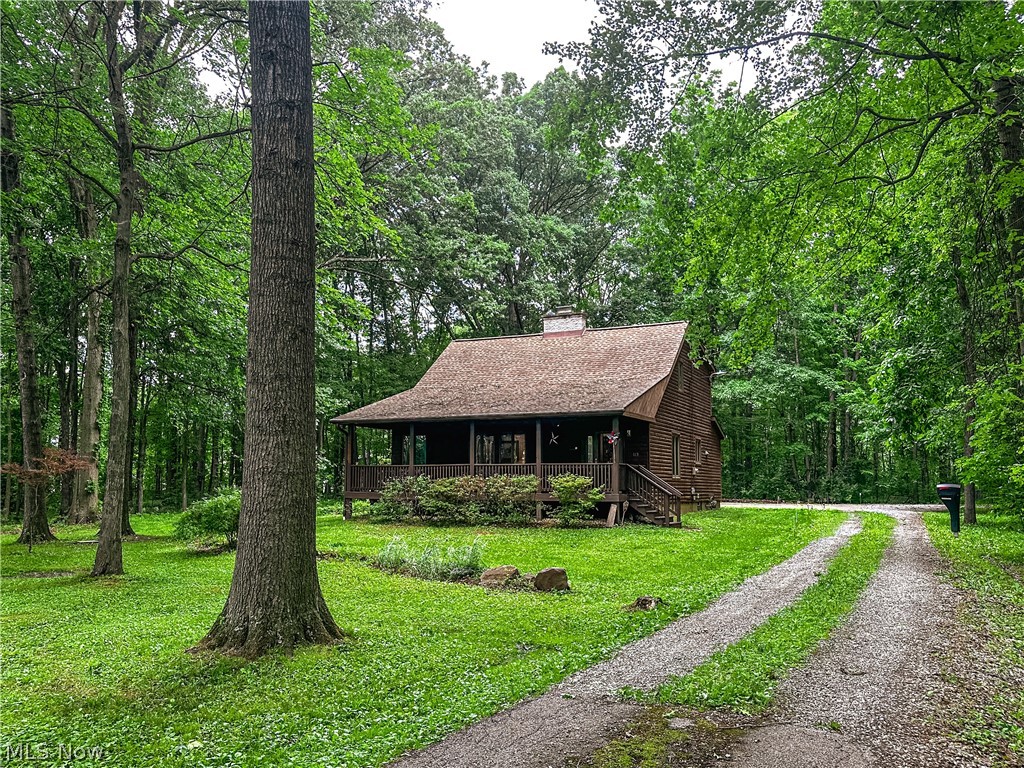 Welcome to 340 Tibbetts-Wick Road, where rustic charm meets peaceful country living. Tucked back from the road and situated on nearly 2 acres, this beautiful log cabin-style home offers privacy, space, and breathtaking views in every direction. The inviting front porch stretches across the home, creating the perfect place to relax and enjoy the peaceful surroundings. Step inside to a welcoming foyer with a coat closet, opening into the spacious open-concept family room, dining area, and kitchen. Natural wood finishes, soaring ceilings, exposed beams, and a stunning floor-to-ceiling brick fireplace create a warm and unforgettable gathering space. Head outside to an entertainer’s dream featuring a covered pavilion-style concrete patio, a four-car garage, heated workshop, and an abundance of parking for guests. The wooded backyard provides a beautiful backdrop, while fencing along the rear property line adds definition to the outdoor space. Back inside the home, the first-floor primary bedroom offers convenience and comfort with double closets, ample storage, and a full bathroom featuring a custom walk-in shower. Upstairs, you’ll find two generously sized bedrooms connected by a Jack-and-Jill bathroom, along with abundant closet space throughout. One of the home’s most impressive features is the private balcony, accessible through sliding glass doors, overlooking the entire property and the stunning living area below. From the open loft, take in views of the exposed wood beams, dramatic fireplace, and surrounding countryside. Every room offers a unique perspective of this remarkable property, making 340 Tibbetts-Wick Road a truly special place to call home.