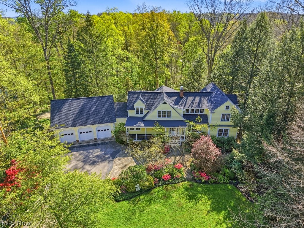 There's a reason certain neighborhoods in Moreland Hills hold onto their people. This one does it with wooded lots, winding roads, and just the right amount of privacy. This colonial is tucked into the trees with a new roof overhead ('26) and sophisticated finishes that still feel comfortable. Inside, the original character shines with beautiful built ins, crown molding, and hardwood floors. Huge windows pull in treetop views that change with the light and the season, and the classic living room fireplace anchors the entire entertaining space. Then there's the kitchen. A couture blue wraps custom Amish cabinetry. Beautiful stretches of quartz, a dedicated prep station, incredible storage, a cozy eat-in nook, and an island that moves easily from Tuesday morning coffee to a holiday party. It's the room the whole house is built around. The family room is the one everyone ends up in--big enough for a mahjong table AND a sectional for movie marathons and cozy nights. A beautiful dining room when the occasion calls for it. Space that bends to whatever your day needs. Upstairs, the primary suite has its own hallway leading to a room with vaulted ceilings, a window seat, walk-in closets, and a spa bath that prioritizes calm over flash. Another en-suite bedroom & two more bedrooms share a beautifully renovated full bath. Outside, a second gravel drive leads deeper onto the property to the party barn which is entirely its own thing. Throw open the windows, string the lights, light the fire. This is where late nights happen. The front yard is fenced for the dogs who've already claimed it and the kids who don't come in until they're called. The covered front porch catches the quiet mornings before the day has opinions. The back deck is made for the kind of dinners that turns into something longer. Boasting Chagrin Falls Schools and minutes to the Village. It's rare to find this kind of setting, these sorts of finishes and this sort of feeling all in one place.