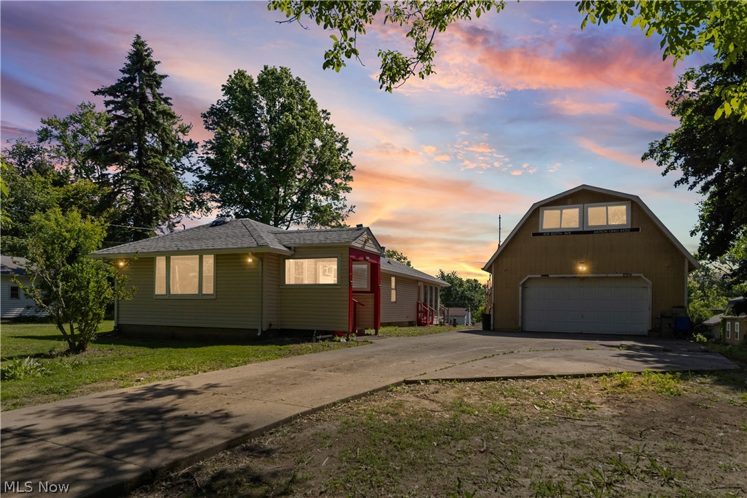 This ranch-style home offering a practical layout and inviting living spaces. The residence features two bedrooms, including a distinctive bedroom with a vaulted ceiling, exposed wood beams, and a prominent skylight that brings natural light into the space. The galley kitchen is equipped with wood-finish cabinetry, white countertops, and wood-finish flooring, creating a functional workspace with ample storage. The spacious living room showcases light-toned tile flooring, a classic wood-burning stove with a tiled hearth, and multiple sliding glass doors that provide direct access to the outdoor deck. Come outside to enjoy the expansive deck, complete with wood flooring and matching wood railings, offering additional outdoor living space. The garage includes an open utility area with a concrete floor, exposed wood beam ceiling, and extensive built-in shelving, providing versatile space for storage, hobbies, or workshop needs. Conveniently arranged on a single level, this ranch home combines indoor and outdoor living areas with functional features throughout.