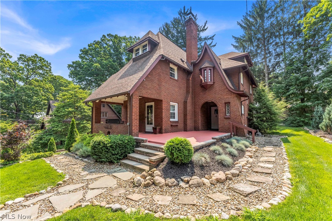 Discover this captivating brick Tudor in West Akron's highly coveted Merriman Valley. Nestled on a scenic, tree-lined street near Portage Country Club and Stan Hywet, this gem perfectly blends original historic character with meticulous modern updates. Spanning more than 2,400 sq ft (plus a 1,000 sq ft basement), this 5-bed, 1.5-bath home features three beautifully finished levels of living space. Inside, fall in love with gorgeous hardwood floors, crown molding, arched doorways, and a cozy wood-burning fireplace in the living room. Host gatherings in the formal dining room, or relax in the sun-drenched sunroom with built-ins. The kitchen offers wood cabinetry, tile flooring, and a nearby half-bath. The second floor hosts a massive primary bedroom featuring its own fireplace and double closets, alongside two additional bedrooms and a beautifully tiled full bath. The third level offers two versatile bedrooms and a large walk-in closet, perfect for a home office or guest suite. The walk-out basement features laundry, ample storage, and easy access to the two-car garage. Outside, enjoy a cozy covered patio and a private backyard. Key updates: fresh landscaping, a new retaining wall, and a widened driveway, new roof (2019; flat roofs replaced in 2016), windows and hot water tank (2015), garage doors & keyless entry (2019), French drains and trench landscaping (2019), and fresh interior paint (2021). Enjoy easy access to downtown Akron & Cleveland. Schedule your tour today!