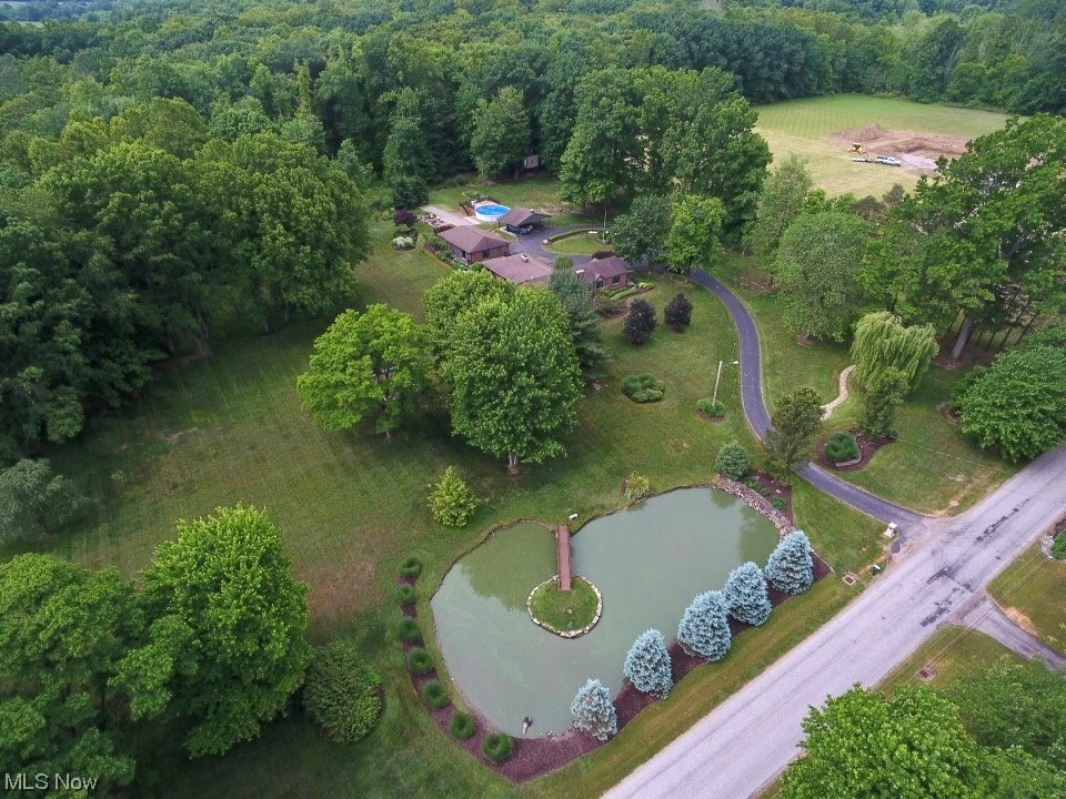 Encompassing 26.28 acres over three parcels, this Hubbard estate has everything you've been searching for in a wonderfully-private location. Tucked away on a quiet township road but not too far from shopping, dining and highways, this property sits back off the road on a perfectly-groomed lot with beautiful pond views in the front, acres of woods in the back and plenty of recreational space in between. This spacious brick home, which has been updated over the years, features a living room with stone fireplace, dining room, remodeled galley kitchen with ample cupboard space, large family room with office nook, generously-sized  primary bedroom with attached bath, two additional bedrooms and a full bath. The basement provides even more usable space with a rec room, bar/eating area, game room, laundry room and storage areas. In all, this home delivers nearly 4,000 square feet of living space spanning two levels. The exterior offers an enclosed patio, one car attached garage, three car detached garage, aboveground pool, lovely brick paver patios, professional landscaping and an expansive lawn. Don't miss out on your chance to own such a special property!