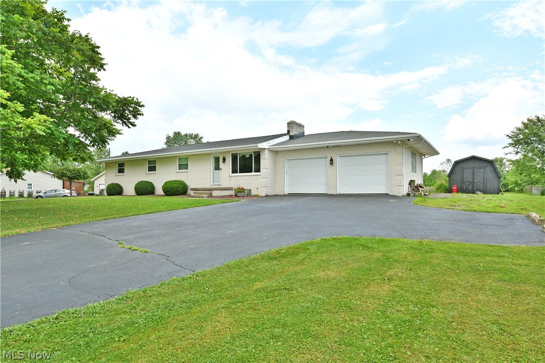 Find the scenic countryside setting you've been searching for with this beautiful all-brick ranch, offering two floors of beautifully finished living space and a highly desirable four-bedroom layout. Perched atop its lot, the home makes a striking first impression as brick stanchions frame the blacktop driveway leading to the attached two-car garage. Manicured landscaping lines the sidewalk, welcoming you to the front entrance. Around back, you'll find a spacious covered patio featuring a unique stone fireplace, creating the perfect space for entertaining, along with a sizeable storage shed for all your outdoor needs. Step inside to a warm and inviting living room where a large picture window fills the space with natural light while a stunning stone fireplace creates an inviting focal point. Just beyond, the expansive kitchen and dining area stretches across the rear of the home. A large center island with an integrated sink anchors the kitchen, allowing you to enjoy peaceful backyard views through the sliding glass doors. A hidden pantry provides additional storage just off the dining area. Down the hall, four generously sized bedrooms with ample closet space provide comfortable accommodations for family and guests alike. The beautifully appointed full bath showcases a relaxing spa-style soaking tub, perfect for unwinding after a long day. The spacious primary bedroom completes the main level with dual closets and its own private full bath. The finished lower level offers exceptional additional living space with multiple recreation and flex areas, along with a convenient laundry room and half bath. Around the corner, an incredible family room steals the show with a striking brick fireplace, dedicated pool table area, and an entertainment-ready bar that's perfect for hosting family and friends. Updates: furnace/AC 2022, HWT 2022, roof 2023, covered patio metal roof 2022, septic 2018, and so much more! Plus a one year home warranty!