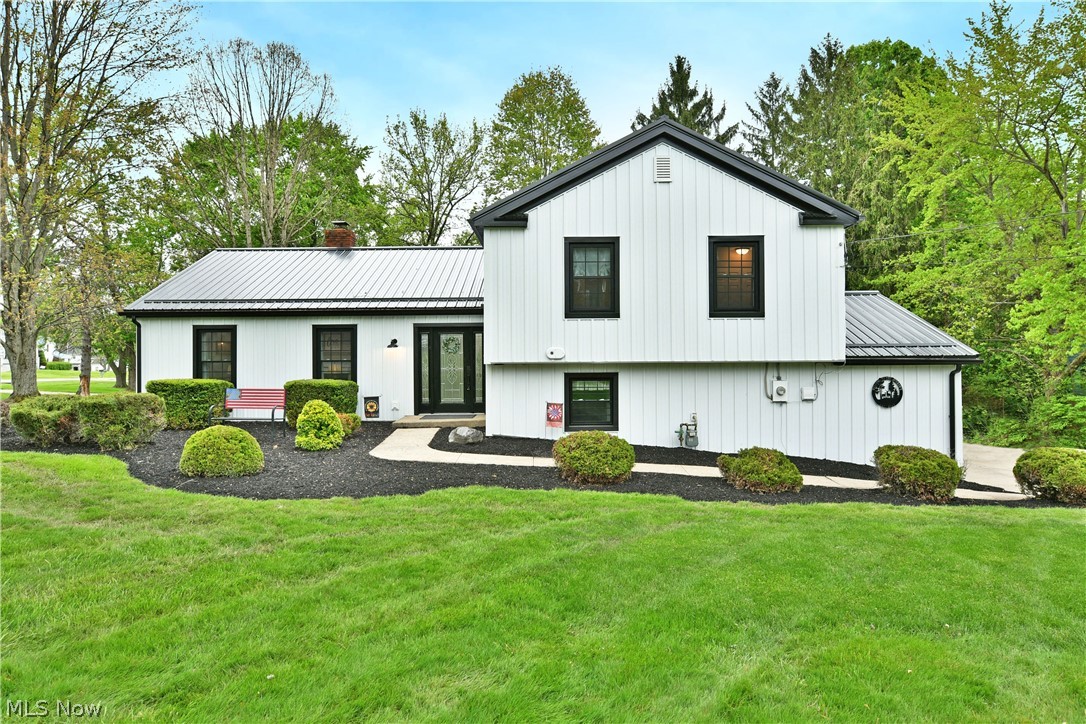 If you’ve been waiting for “the one” in Garrettsville—this is it! This masterfully renovated split level showcases an endearing, three-bedroom layout that’s sure to impress. A curb appeal champion, the home takes full advantage of its prominent corner lot, standing out from the crowd with its incredible, black and white steel exterior surfacing to include the siding and roof. This high contrast look exudes quality with long lasting style, all accented by manicured mulch and stone beds that hide multiple patio spaces that includes a covered and elevated rear section for warm summer evenings. Inside, the glass laden entry door opens to the welcoming foyer. Hardwood style flooring runs underfoot by the coat rack and continues into the fantastic living room where a large fireplace joins the lattice lined windows and illustrious recessed lighting. Around the corner, enjoy your favorite meals in the formal dining area, overseeing the window lined rear family room and its tall ceilings that join towering shelving for a perfect home office, study or home library. The central kitchen brings the heat with striking, butchers block countertop surfaces and artful lighting choices that pair with updated cabinetry and a hidden pantry. Upstairs, revel in the master suite and its custom private bath, brimming with stone and glass work. Two additional bedrooms accompany a brightly lit full bath while second floor laundry services end the hall. Down at the lower level, hidden utility access joins a half bath while a walk-out family room enjoys its stained wood built-in cabinets. Recent updates include 50-year metal roof installed 2023, 50-year board and batten metal siding 2023, vinyl windows 2023, seamless gutters and gutter guards 2023, bathroom and kitchen remodel 2025 and many more! Prime location near the library, schools, Village park, Headwater Trail and Village Business District. The sellers are MOTIVATED and waiting for your offer!!