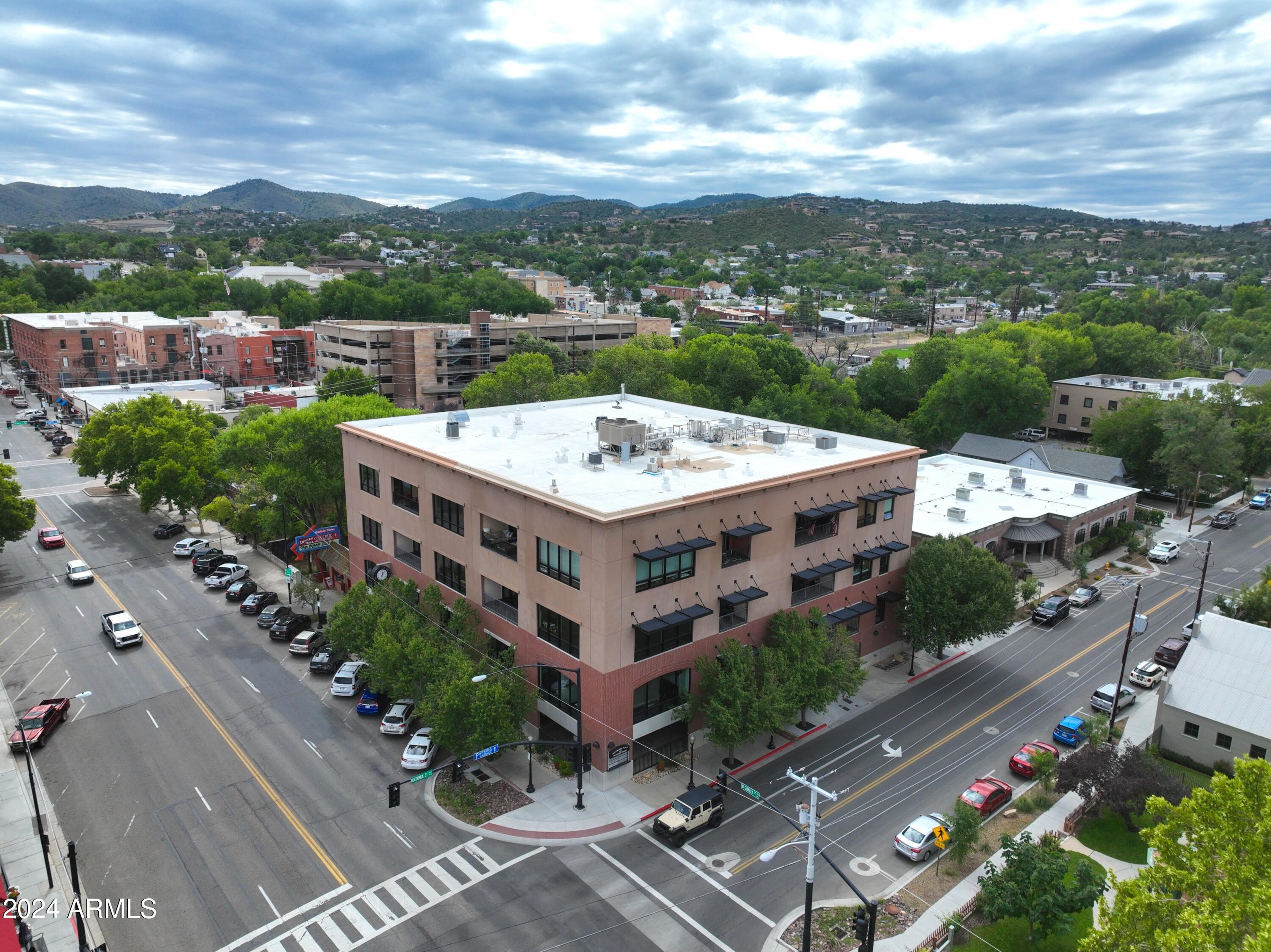 Luxury condo in the heart of downtown Prescott, one block from the Courthouse Plaza. Two bedrooms plus office, 2-bath unit features a private elevator with coded access, 12-14 ft ceilings, large windows, and an open floor plan with views of Gurley Street and Granite Mountain.
Gourmet kitchen has Caesarstone countertops, custom cabinetry, wine storage, two large islands, stainless steel appliances, and a Sub-Zero refrigerator. The living area has a gas fireplace with stone surround and direct access to the private terrace. The spacious primary suite offers floor-to-ceiling windows, access to the terrace, two custom walk-in closets, and a large ensuite bathroom with jetted soaking tub, walk-in shower, and dual vanities.
Guest bedroom includes custom built-in closet and space for a desk or sitting area.  Large office is being used as the third bedroom.  Polished concrete floors throughout with bleached wood flooring in the primary suite.  Low-maintenance finishes are ideal for full-time or lock-and-leave living.  Located in a secured building one block from the courthouse square, shops, dining, galleries, and local events.
