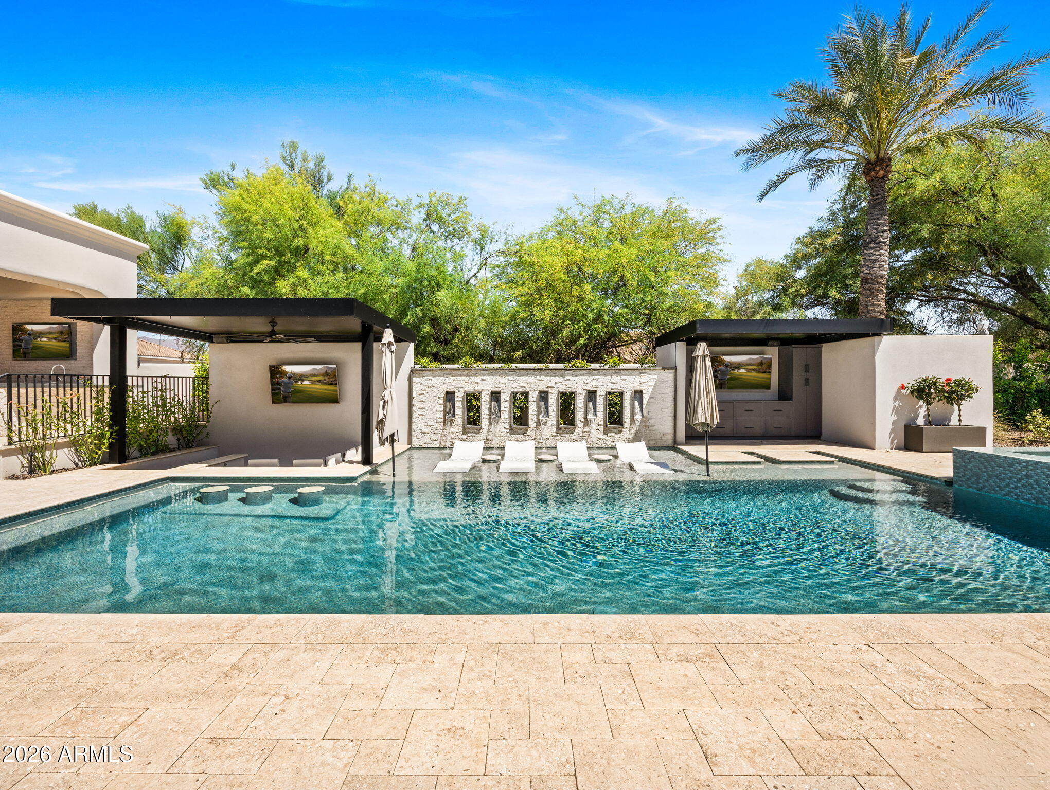 Experience the pinnacle of sophisticated living in this fully reimagined contemporary smart home in the heart of the Cactus Corridor. Fully integrated with Control4 automation, the residence features an open-concept chef's kitchen with a built-in espresso station, dual dishwashers & premium appliances. The expansive great room transforms into a private cinema with a concealed projection screen, while floor to ceiling sliders lead to the ultimate outdoor retreat.
The resort-style backyard is an entertainer's dream, boasting a heated & chilled pool with a swim-up bar, zero-edge spillover spa & five outdoor TVs. An elevated culinary pavilion features a teppanyaki grill, dual grilling stations & a fire bar social hub. For active living, enjoy a private pickleball/sport court, putting green & lush turf zones surrounded by over height privacy walls. Automotive enthusiasts will appreciate the extended length 3 car garage, featuring soaring ceilings with the ideal clearance to add vehicle lifts.
The primary suite serves as a true wellness sanctuary, complete with a private sitting room, infrared sauna, steam shower and soaking tub. All secondary bedrooms are ensuite with walk-in closets.