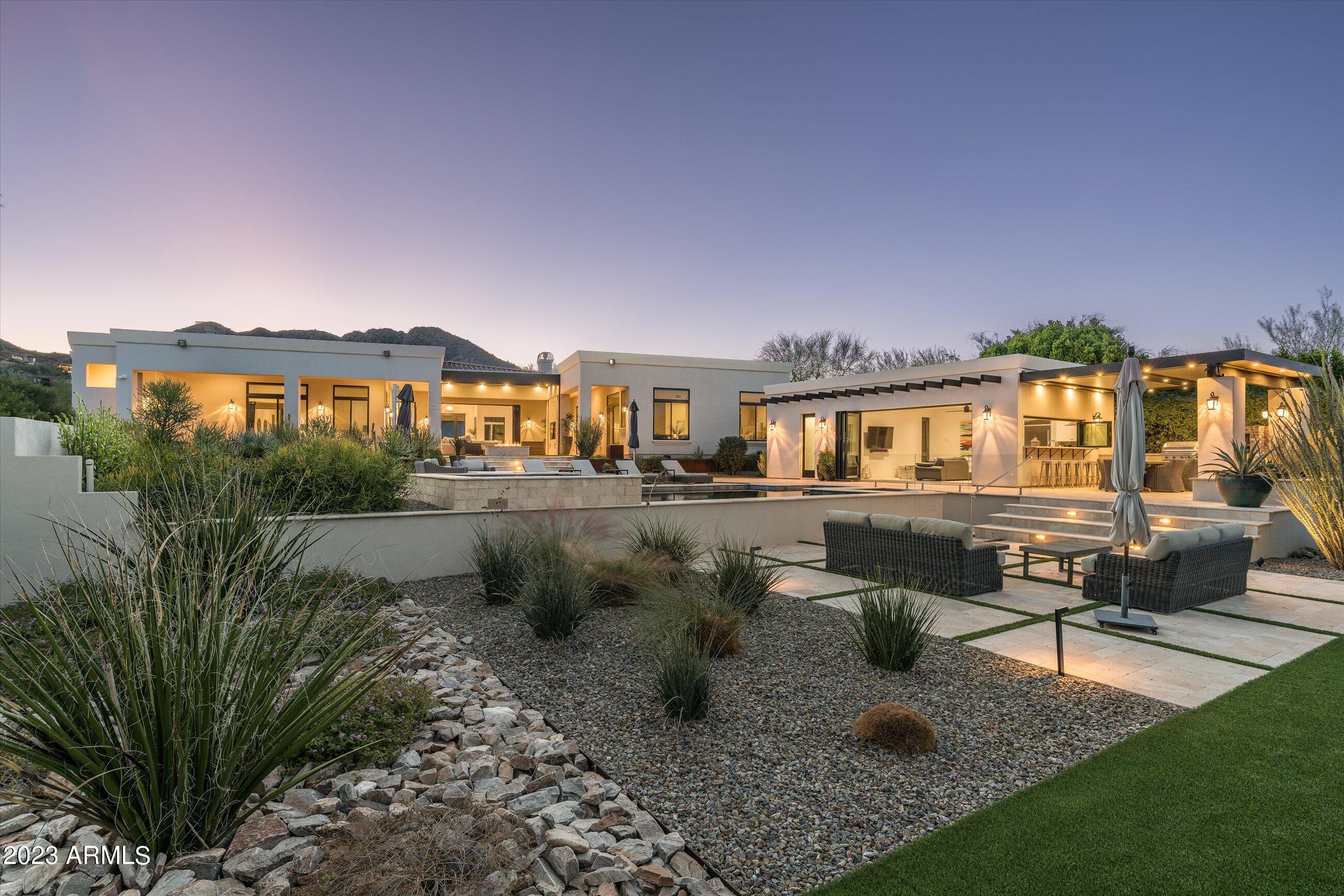 Indulge in the pinnacle of luxury and relish breathtaking elevated mountain views in the heart of Paradise Valley in this remarkable Emerald Level, Certified Green Home (the most stringent certification and highest achievement in sustainable building) with owned solar panels. This soft contemporary custom home blends sustainability with elegance, offering 5 bedrooms, 5.5 baths, and a 4-car garage. A designer glass door welcomes you at the entry, leading to an open floor plan with soaring ceilings and wall-to-wall engineered oak wood floors and an elegant fireplace. The gourmet kitchen is a chef's dream, featuring quartz countertops, a Wolf stainless steel gas range, microwave, and an oversized center island with quartzite, adorned with overhead designer pendant lighting and eat-up bar. seating. The dining room with large windows adds an element of sophistication, while the powder room boasts a designer wood counter and vessel sink. Split dual primary suites and luxurious spa-like baths elevate this home to an unparalleled level of luxury and comfort. Step into the backyard oasis to discover a resort-style heated pool and spa, a ramada with a grill, a brick fire pit, a spacious covered patio, and captivating city light and mountain views. Additionally, this home includes a spectacular guest casita overlooking the backyard paradise, complete with a kitchen, living area, and a guest suite. Enjoy the gorgeous outdoor dining area with travertine surround, creating an inviting atmosphere for entertaining or relaxation. This residence is a must-see for those who appreciate designer elegance and luxurious amenities that redefine opulence and cater to the most discerning tastes.