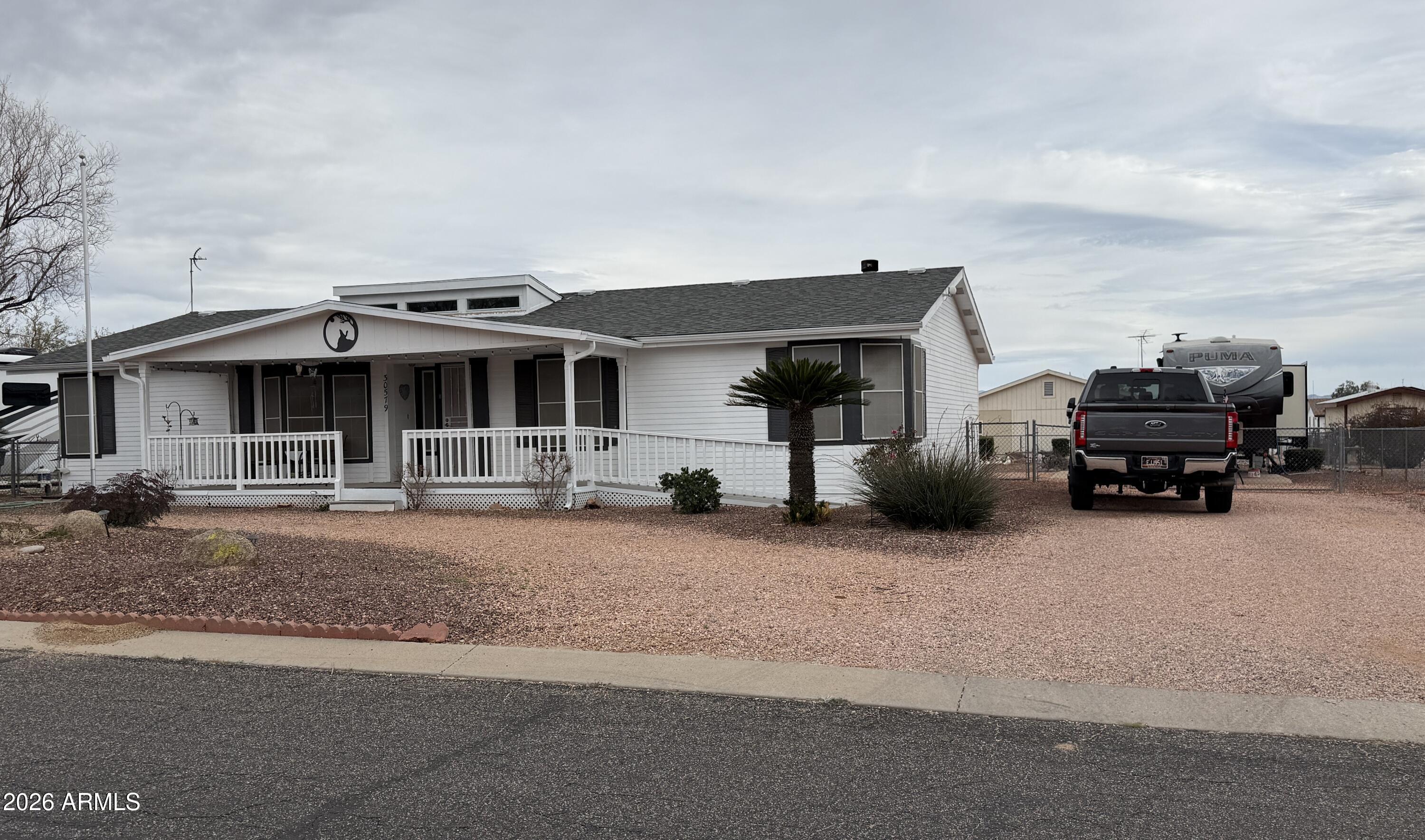 Discover desert living at its finest on this expansive North Ranch lot in Congress! This immaculate 1-bedroom, office,& Guest room , 2-bath home features 1,790 square feet of open-concept living with a fireplace-warmed family room and chef-friendly kitchen. The generous property includes a detached 2-car garage with workshop space, circular driveway, and full RV hookups behind a fenced backyard. New Irrigation System too! Enjoy front porch relaxation and back patio entertaining in this well-maintained retreat, complete with new roof and thoughtful upgrades throughout.
A NON-AGE Restricted Community