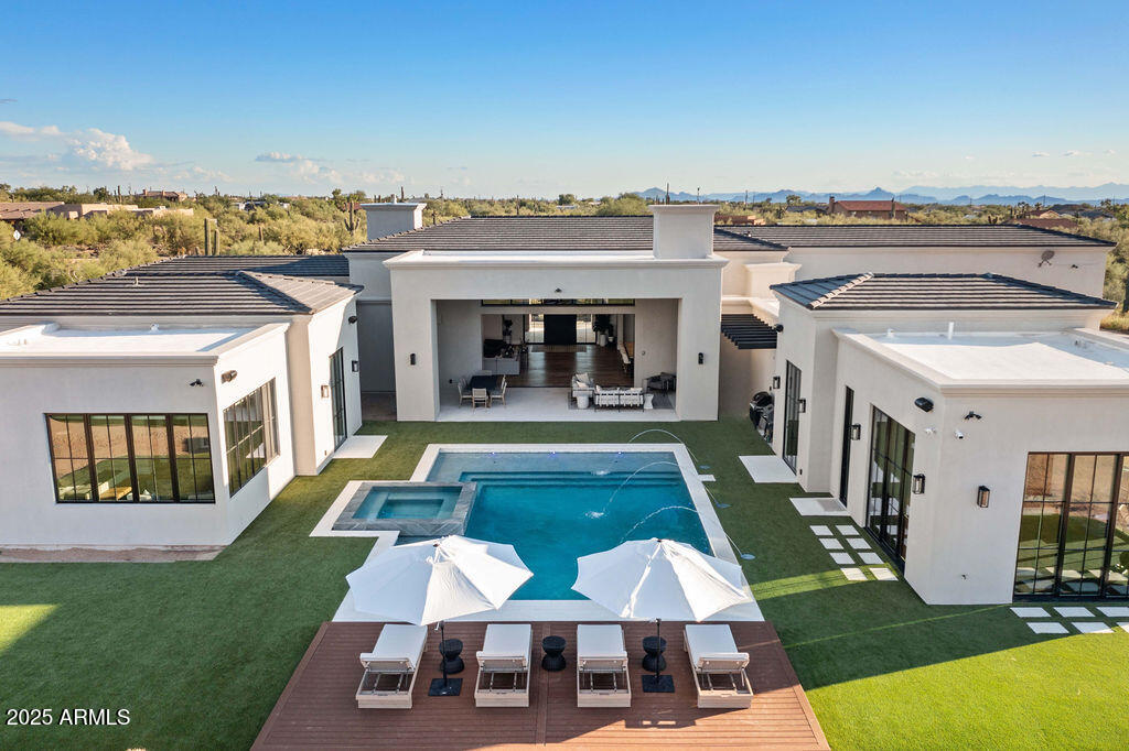 Welcome to your dream home in the heart of North Scottsdale! Built in 2022, this luxury estate sits on nearly 2.2 acres and offers over 6,000 sq ft of thoughtfully designed living space. With 5 bedrooms, 7 bathrooms, and a separate guest/in-law suite with its own entrance and garage, there's room for everyone. Every bedroom features its own en-suite bath and custom walk-in closet. The gourmet kitchen is a showstopper with two massive 13-foot Quartzite islands, Thermador appliances, a pebble ice machine, and a walk-in pantry—perfect for cooking and entertaining. Quartzite countertops flow throughout the home, including the outdoor BBQ area. Enjoy indoor-outdoor living with a 20' automated sliding glass wall opening to a north-facing backyard oasis. The 20,000-gallon saltwater pool and oversized 10'x10' hot tub feature a Baja shelf, deck jets, LED lighting, and an infinity spa. There's over 5,000 sq ft of artificial turf, a 1,700 sq ft grassy play area, and a full outdoor kitchen with a gas BBQ, sink, and mini fridge. Inside, you'll find soaring ceilings (up to 14'), European white oak wood floors, a climate-controlled wine cellar, teen room, home gym with sliding doors, and a stylish mudroom with custom cabinetry. The home is tech-savvy too; equipped with a smart wiring system, security cameras, in-ceiling speakers, and hardwired ethernet in every room. Car lovers, take note: the 7-car garage spans over 2,300 sq ft and includes a 45' RV bay and space for 12+ cars with lifts. The entire home, including the garage, is spray foam insulated for energy efficiency. Plus, enjoy Anderson windows and doors, a custom 10' pivot front door, and automated Hunter Douglas window coverings with blackout shades in all bedrooms. Located close to world-class golf, dining, shopping, and top schools. This North Scottsdale estate checks every box for luxury, privacy, and comfort.