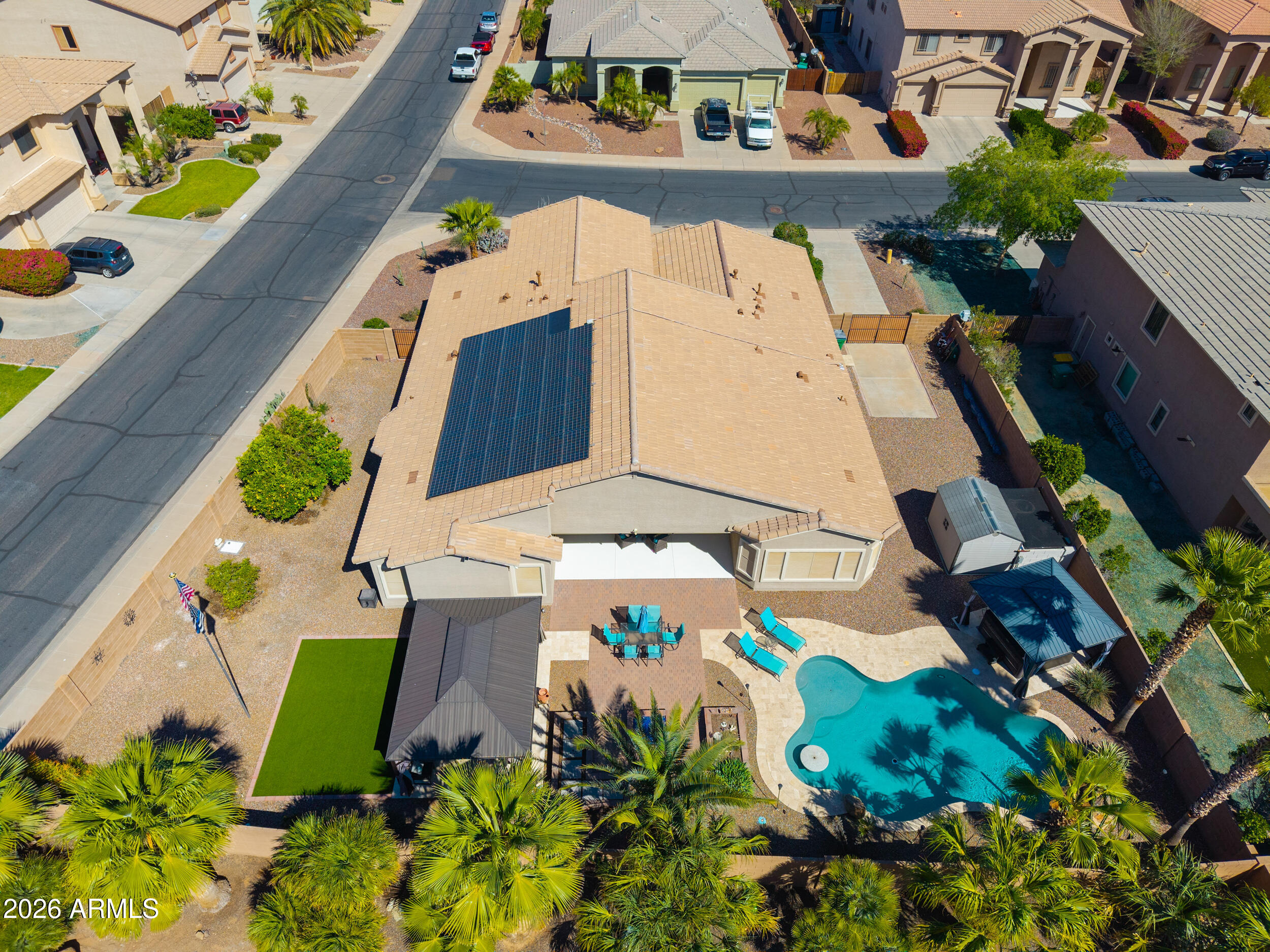 Beautiful Hacienda-built 2x6 construction single-story home offering 2,860 sq. ft., 4 bedrooms plus a den, 2.5 baths, and a 3-car garage with dual gate slab parking and resort-style backyard. This well-maintained home features an OWNED SOLAR SYSTEM providing excellent energy efficiency and major utility savings, along with 2 NEW A/C & FORCED AIR HEAT SYSTEMS for year-round comfort. Additionally, a NEW ROOF(2024) adds value and peace of mind. The kitchen is designed for both everyday living and entertaining with granite countertops, dual ovens, a gas cooktop, and plenty of cabinet and counter space. The spacious floorplan includes a large primary suite with private backyard access, a walk-in shower, a separate soaking tub, dual sinks, and a generous walk-in closet. (see additional remarks) Three oversized secondary bedrooms plus a versatile den offer flexible living space for a home office, playroom, or guest area. Step outside to a backyard built for enjoying Arizona living, featuring a heated pool with a waterfall, a separate hot tub, an outdoor gas firepit, and two gazebos--one wired for a hot tub and the other set up for an outdoor kitchen with a premium BLAZE grill and a separate griddle. Mature desert landscaping includes saguaros, palm trees, and fruit trees, all supported by a PVC irrigation system. Additional features include sunscreens, a storage shed on a cement pad, and excellent curb appeal. This move-in-ready home combines major upgrades, energy efficiency, and a fantastic backyard just in time for summer!