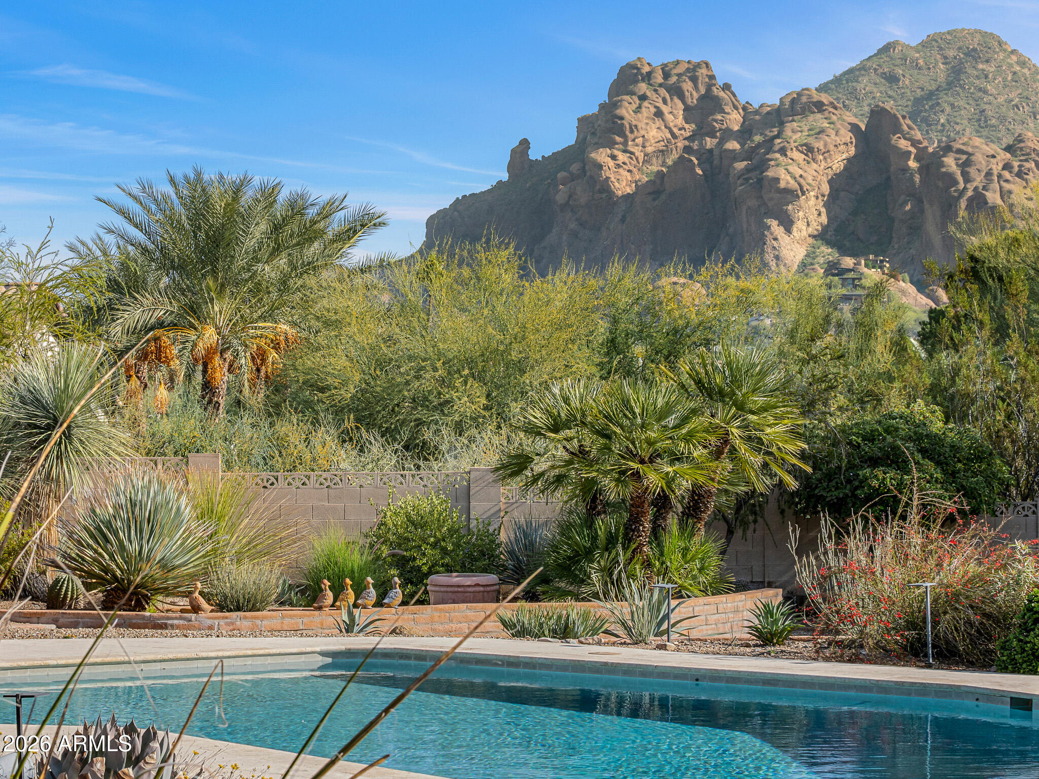 Tucked within the heart of Paradise Valley, this refined Southwestern Modern residence offers a serene blend of luxury and relaxed elegance, centered around a tranquil courtyard and soothing water features that create a true private oasis. Designed with effortless flow, the split floor plan highlights a stunning, newly updated primary suite, a true designer showcase, while thoughtfully curated interiors invite both comfort and sophistication. The chef's kitchen is a masterpiece of form and function, featuring professional grade design and top-tier appliances, including three ovens, a Teppanyaki side plate, warming drawers, and an integrated espresso machine. Entertaining is effortless with a generous dining room, multiple courtyards and patios, and a beautifully appointed detached casita featuring one bedroom and one bathroomperfect for guests seeking privacy and comfort. Each space is thoughtfully positioned to embrace views of Camelback Mountain and the peaceful sounds of water flowing through the property. The primary suite is a luxurious retreat, complete with a cozy gas fireplace and a breathtaking bathroom featuring a walk-in shower, spa-inspired design, and a massive walk-in closet. A built-in television within the mirror ensures you never miss the news or your favorite game, even while getting ready. Set on over an acre, the grounds showcase a recently updated pool and spa surrounded by mature landscaping and expansive entertaining areas, perfect for hosting or unwinding in complete privacy. Additional features include a temperature-controlled wine cellar, prep kitchen, oversized laundry room, and a rare four-car garage. This is refined Arizona elegance at its finestwhere tranquil courtyards, flowing water, and timeless design define luxurious Paradise Valley living.