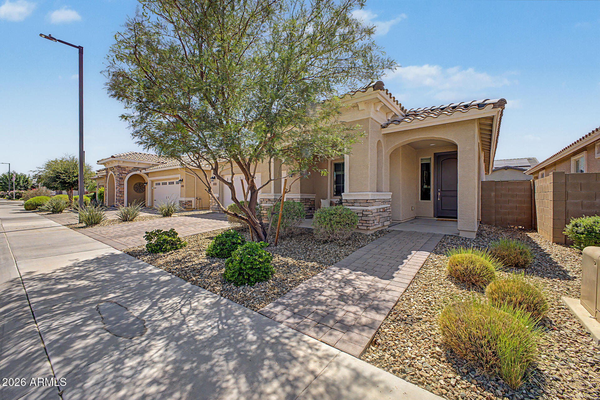 Find your ideal retirement haven in the 55+ gated Community of Heritage Asante! This beautiful 2-bedroom home displays a front porch, manicured landscape, stone accent details, & a 2-car garage w/paver driveway. The interior exudes refined style with tall ceilings, tons of natural light, recessed lighting, a designer palette, wood-look tile flooring in common areas, and soft carpet in bedrooms. You'll love the seamlessly flowing open layout for everyday living & entertaining! The impeccable kitchen boasts SS appliances, quartz counters, mosaic tile backsplash, ample white cabinetry, and an island w/pendant lights over the breakfast bar. Large main bedroom has an ensuite, featuring dual vanities & a walk-in closet w/direct laundry room access. Relax under the covered patio of your backyard! Residents of Heritage Asante enjoy resort-style amenities designed for active adult living, including a clubhouse, fitness center, resort-style pool & spa, pickleball courts, bocce ball courts, and scenic walking trails. The community also features lakes, dog parks, fire pits, and a unique putting course, creating a fun & relaxing atmosphere year-round. Don't miss this opportunity!