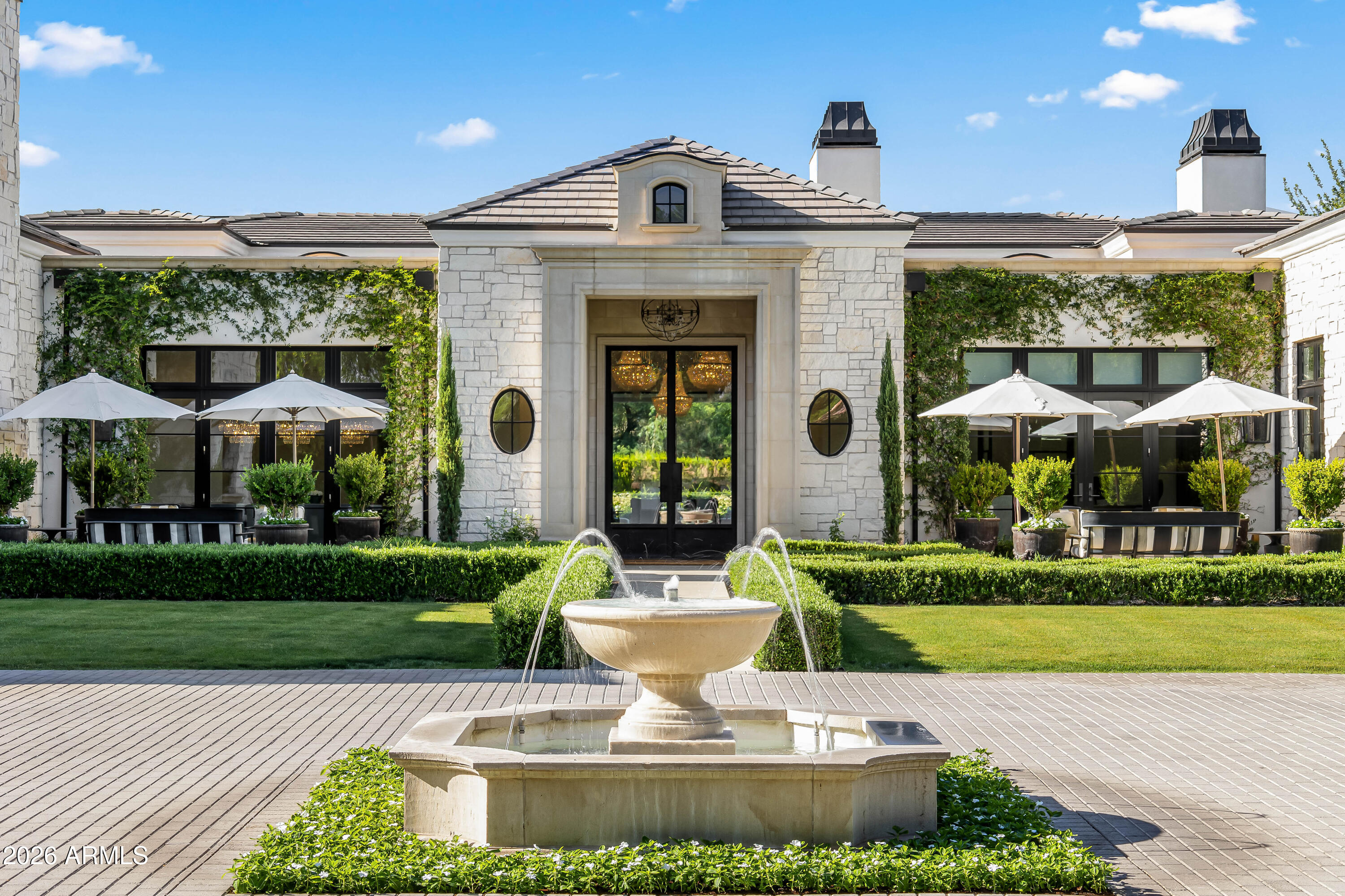 Tucked behind gates on a quiet cul-de-sac in the heart of Paradise Valley, this rare nearly 1.5-acre estate offers exceptional privacy, timeless architecture, and resort-style living. Welcomed by a sparkling fountain, the home's sophisticated design features soaring ceilings, designer lighting, and walls of sliding glass and French doors that fill the interiors with natural light. Designed for seamless indoor-outdoor living, the expansive great room showcases a gas fireplace and retractable wall of glass opening to the breathtaking backyard. Entertain effortlessly with a formal dining room and elegant living room complete with a wet bar and retractable wall of windows to enjoy Arizona weather. The chef's kitchen is the heart of the home, featuring double islands, premium appliances, multiple ovens, wood-beamed ceilings, an eat-in dining area, and a fully equipped butler's pantry and prep kitchen. The luxurious primary suite offers a private retreat with its own fireplace, direct backyard access, dual custom closets, dual vanities, a freestanding soaking tub, oversized walk-in shower, and separate toilets. The resort-inspired backyard features a custom heated pool and spa, outdoor BBQ, outdoor fireplace, expansive covered and uncovered patios, and lush manicured grounds framed by mature trees and landscaping. Additional highlights include a dedicated expansive office with french doors and exterior access and a spacious 4-car garage. Ideally located in the highly sought-after "3 C's" school district and near Arizona's world-class resorts, golf, hiking, fine dining, and upscale shopping.