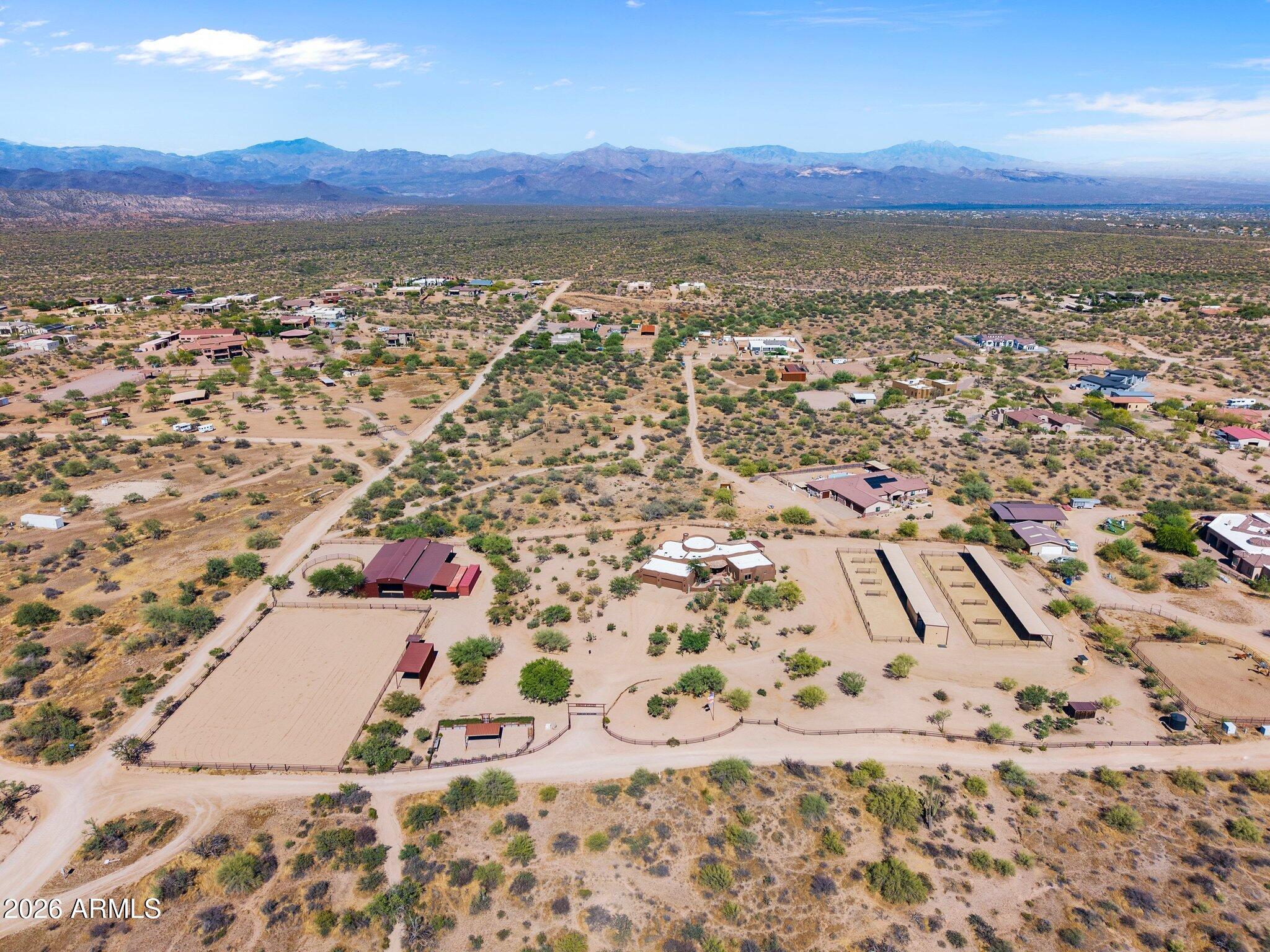 Some properties hold you still the moment you arrive. This hilltop 5 acre horse ranch -- adjacent 5.8 acres available -- borders Tonto Nat'l Forest with Granite Mountain filling the horizon.

The centerpiece is a custom 60x80 steel barn with six 20x20 covered stalls, a reclaimed wood tack room, 120x200 professional arena with announcer's booth, 60-foot round pen, and solar entry gates. A second engineered facility (comp. Nov. 2024) adds 10 covered pens, 39 configurable gates, tack and supplement rooms, and a private well. Suitable for cattle or horses.

Inside, wagon wheel timber beams crown the great room, a chef's kitchen delivers 6-burner gas, double ovens, and chiseled granite, and the primary suite opens to mnt views and a fireplace over the jacuzzi tub. Properties built like this rarely come available! Arrange a virtual tour if you want to get a sneak peek.