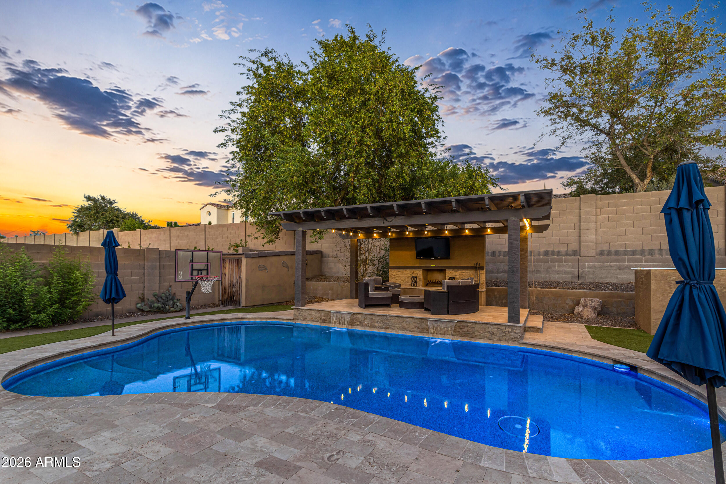Nestled in the foothills of Estrella Mountain, this stunning two-story home welcomes you with a spacious, open floor plan. The seamless main level flows into a large kitchen featuring a center island--ideal for entertaining family and friends. Upstairs, a versatile loft leads to all bedrooms, including the impressive primary suite. This private retreat boasts dual sinks, a deep soaking tub, a separate walk-in shower, and a large walk-in closet. 
The highlight of this property is the spectacular backyard oasis. Enjoy gorgeous mountain views, a sparkling pool, a custom putting green, and comfortable seating areas. Unwind under the massive pergola, complete with a cozy outdoor fireplace and TV, making this the absolute perfect spot to relax and enjoy your new lifestyle