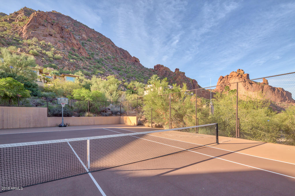 High on Camelback Mountain, in the Sanctuary complex, showcasing a perfect silhouette view of the Monk, city lights and mountains this unique 5 bdrm, 5610sf retreat has its own tennis court. Enjoy concierge and hotel services of the Sanctuary Resort. Natural light invades the large great room with vaulted ceiling,oak flooring and window wall opening to a spacious tiered view patio with infinity pool and bubbling spa. Split master bedroom has a sensational glass walled exercise rm opening to the view patio. Split locked private wing with 2 ensuite bedrooms can function as a guest suite or rental. Lower level has additional 2 ensuite bedrooms flanked by a central living rm with kitchenette + exercise rm with pool bathrm + shower. This special view property offers multiple use possibilities!