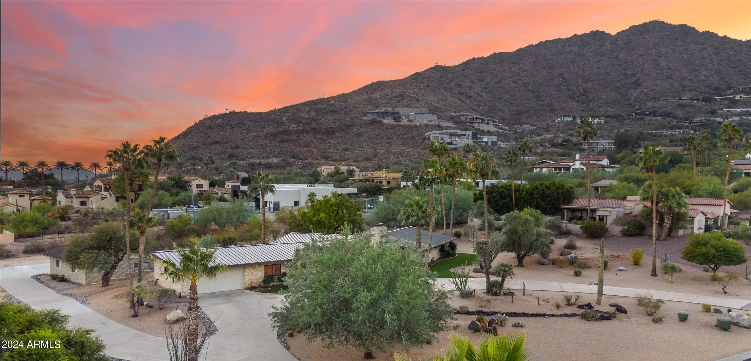 NESTLED AGAINST THE MAJESTIC BACKDROP OF CAMELBACK MOUNTAIN, THIS MID-CENTURY MODERN GEM SEAMLESSLY INTEGRATES TIMELESS ARCHITECTURAL ESSENCE WITH LUXURIOUS MODERN COMFORTS AND SITE ON AN ACRE AND HALF LOT! THE EXTERIOR FEATURES TEXAS LIMESTONE, A SLEEK METAL ROOF, AND THE SOPHISTICATION OF NEW FLEETWOOD WINDOWS & DOORS, EFFORTLESSLY LINKING THE OUTDOORS WITH THE INTERIOR, UNVEILING MESMERIZING VIEWS OF CAMELBACK MOUNTAIN. STEP THROUGH THE INVITING CUSTOM GLASS DOOR INTO THE FOYER, WHERE RAISED CEILINGS LEAD YOU TO THE HEART OF THE HOME - THE GREAT ROOM. THIS WELCOMING SPACE BOASTS AN EXPANSIVE WALL OF WINDOWS THAT FRAMES THE ENCHANTING BACKYARD GREENERY, AND A GRAND FIREPLACE ADORNED WITH STACKED STONE AND COPPER SURROUND ACCENTS, CREATE A COZY HAVEN FOR INTIMATE GATHERINGS. ADJACENT TO THE GREAT ROOM, THE CONTEMPORARY KITCHEN BECKONS WITH ITS SLEEK DARK CABINETRY, A STYLISH GLASS TILE BACKSPLASH, AND SUB-ZERO AND WOLF APPLIANCES. THE 6-BURNER GAS RANGE, FEATURING AN OVERHEAD WATER FAUCET, ADDS A TOUCH OF CULINARY SOPHISTICATION TO THIS INVITING SPACE. THE OVERSIZED CENTER ISLAND BECOMES A NATURAL FOCAL POINT FOR SOCIALIZING AND ENTERTAINING GUESTS. MOVING SEAMLESSLY INTO THE DINING ROOM, DISCOVER A CHIC BUILT-IN WET BAR COMPLETE WITH A CUSTOM WINE FRIDGE AND SINK, ENHANCING THE HOME'S LUXURIOUS APPEAL. EACH BEDROOM IS A PRIVATE RETREAT, BOASTING ITS OWN EN-SUITE BATH THAT SEAMLESSLY BLENDS MID-CENTURY MODERN AESTHETICS WITH CONTEMPORARY LUXURY. STEP OUT ONTO THE COVERED PATIO WHERE THERE IS PLENTY OF ROOM TO CREATE AN OUTDOOR DINING HAVEN OVERLOOKING THE LUSH YARD - A PERFECT SETTING FOR ENJOYING SUNSETS AND TRANQUILITY. STEP OUT ONTO THE COVERED PATIO TO EXPERIENCE AN OUTDOOR DINING HAVEN OVERLOOKING THE LUSH YARD, ENHANCED BY THOUGHTFUL LANDSCAPING AND IRRIGATION LINES, AS WELL AS CONCEPTUAL DRAWINGS FOR A STUNNING LANDSCAPE AND POOL DESIGN. THE RARE 8-CAR GARAGE, BOASTING PAVERS, NEW AC, AND EPOXY FLOORING, IS NOT JUST A STORAGE SPACE BUT AN EXTENSION OF THE HOME'S AESTHETIC, WITH RETAINING WALLS, A NEW ROOF, AND ATTIC VENTING FOR OPTIMAL FUNCTIONALITY. ADDITIONAL UPGRADES INCLUDE: THE PROPERTY HAS BEEN OUTFITTED WITH A TANKLESS HOT WATER HEATER, NEW SEPTIC TANK, $20,000 IN STATE-OF-THE-ART PROPERTY SECURITY CAMERAS, BRAND-NEW HVAC UNITS FOR OPTIMAL CLIMATE CONTROL. THE HOME IS ALSO EQUIPPED WITH A SAVANT SYSTEM FEATURING SMART HOME CAMERAS FOR FULL SECURITY, SURROUND SOUND FOR AN IMMERSIVE AUDIO EXPERIENCE, AND $20,000 WORTH OF ALL-NEW HUNTER DOUGLAS ELECTRONIC SHADES. TO COMPLETE THE PICTURE OF LUXURY LIVING, A WHOLE-HOUSE WATER FILTRATION SYSTEM ENSURES A CONSTANT SUPPLY OF PRISTINE WATER THROUGHOUT THE RESIDENCE. DON'T MISS OUT ON THIS INCREDIBLE OPPORTUNITY TO MAKE THIS HOME YOUR OWN, CALL US TODAY TO SCHEDULE A PRIVATE SHOWING.