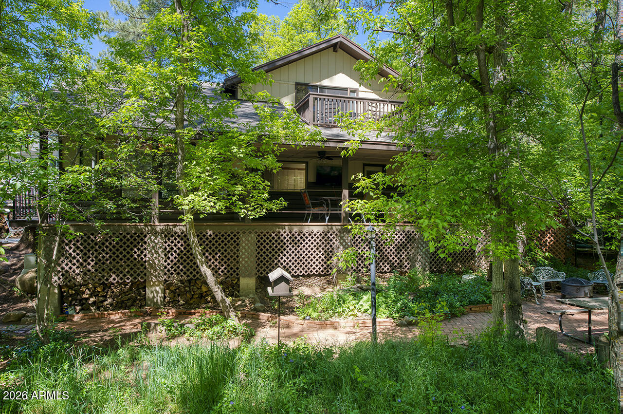 Two-story log-sided cabin in Christopher Creek just outside Payson, Arizona. 2 bedrooms, 2 bathrooms, loft, office, 1,869 sq ft on a wooded lot with no HOA. Most people don't believe a place like this exists in Arizona. Towering pines, mature oaks, AZ Black Maple trees, crabapple trees, grape vines, lavenders, ferns, wildflowers, and a seasonal creek bed, all on one property. An entire ecosystem you never knew Arizona had. As soon as you pull up, winding brick pathways guide you through the yard past a decorative wooden footbridge, a porch swing under the trees, a fire pit patio, and a picnic area all shaded by a canopy so dense every season brings a completely different feel to this property. A ''Welcome'' sign greets you at the covered front porch and deck where you can sit with your morning coffee and watch the elk, deer, squirrels, blue jays, turkeys, and other wildlife. Step inside and see the beautiful hardwood baseboards and trim, and the brand-new 22m Luxury Plank vinyl flooring runs throughout the main level. The living room is the heart of this home with vaulted ceilings, skylights pouring in natural light, and a wood-burning fireplace installed in 2024 that will keep you warm on those cold mountain nights. The kitchen connects right to the living and dining area with newly updated appliances that include an electric stove, built-in microwave, dishwasher, disposal, refrigerator, walk-in pantry, and additional storage under the stairs. Everything you need and nothing you don't. Head upstairs to the master suite with a full bathroom and step out onto the balcony for tree-top views you won't find anywhere else. Yes, this home has 2 separate decks! The loft overlooks the living room below and works perfectly as a reading nook, guest space, or second office. The separate den/office is also upstairs, giving you a quiet, dedicated workspace away from the main living areas. Tons of storage throughout the home, you won't be left looking for space. Back on the main level, the second bedroom has easy access to the second full bathroom. Now let's talk about the outside, because this property is something special. Brick pathways connect the covered patio, multiple seating areas, a storage shed, a bridge, and a workshop. The detached carport keeps your vehicle covered, there's RV hookup & RV parking for your toys, and enough space to park 8 vehicles. Chain link fencing secures a majority of the perimeter. No HOA fees. Christopher Creek sits just off Highway 260 in Gila County, less than 25 minutes from downtown Payson where you'll find shopping, dining, and everything you need. Whether you're looking for a mountain second home, a vacation rental property, or a permanent residence, this home in the pines is the one you've been searching for!