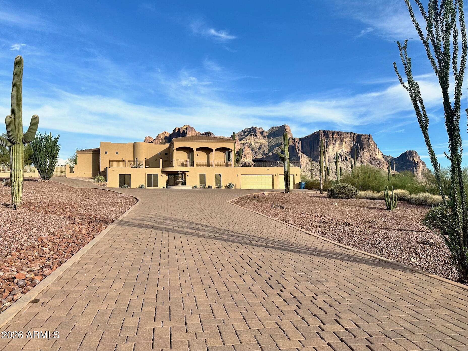 A showpiece in the desert, this custom 3,780 sq ft estate sits gracefully on 1.25 acres, where luxury meets wide-open sky. With 4 bedrooms and 3 full baths, every inch feels intentional, but the real magic starts in the stunning round great room, where walls of glass frame the Superstition Mountains like living art. Sunsets here? Not a view... a nightly performance. The kitchen flows effortlessly into the heart of the home, elevated by automated window blinds that set the mood with a touch. The primary suite is its own retreat, complete with a cozy fireplace and generous his-and-hers closets complete with washer and dryer for laundry convenience. Step outside and you're in full resort mode: sparkling pool, putting green, and an outdoor kitchen/BBQ setup that practically begs for sunset gathering and slow weekends. A wraparound deck delivers 360-degree views that remind you why you chose Arizona in the first place.
Downstairs, the guest suite offers privacy with a full bath, washer/dryer, and a game room and perfect for visitors or that one friend who never leaves. Permanent Everlights trace the home's perimeter, adding year-round ambiance and effortless style. Plus, it's strategically located near lakes, parks, hiking trails, golf courses, shopping spots, and restaurants. The ideal blend of comfort and convenience! This isn't just a home, it's a front-row seat to the desert's greatest hits.  Come tour today!