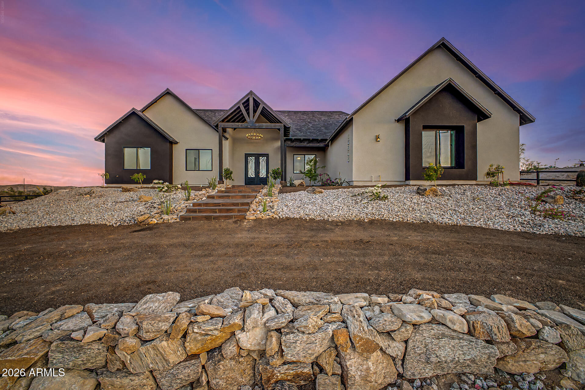 Nestled on an elevated hillside in Buckeye, AZ, this stunning custom home offers breathtaking panoramic views of the surrounding mountains and city lights--perfectly blending peaceful desert living with modern comfort.
This beautifully designed residence features 4 spacious bedrooms, 3 bathrooms, and a custom 3-car garage, all with no HOA and horse privileges, giving you the freedom and space you've been looking for.
Step inside to an expansive open-concept layout highlighted by a chef-inspired kitchen with abundant cabinetry, a large center island, stainless steel appliances, and ample storage for all your culinary needs. The home also features a stylish entertainment center and dry bar, ideal for hosting and everyday enjoyment. The vaulted ceilings with decorative wood beams create a warm, rustic charm that perfectly complements the home's country-inspired design, while maintaining a modern, elegant feel throughout.
The primary suite is a true retreat, offering private access, a luxurious bathroom with a jetted soaking tub, dual sinks, bidet, and a sleek walk-in shower. The spacious walk-in closet is thoughtfully designed with built-in cabinetry and a center island for added convenience and organization. Each additional bedroom is generously sized and includes ceiling fans for comfort. One of the secondary bathrooms also features a bidet, and all bathrooms showcase beautiful tile work with glass shower enclosures.
Additional highlights include:
Farm-style light fixtures throughout
Epoxy-coated garage for durability and style
Inviting front porch with custom wood detailing that enhances the home's character and creates a welcoming entrance
Professionally designed desert landscaping
This one-of-a-kind property offers the perfect combination of custom craftsmanship, space, and unbeatable views--a rare opportunity to own a true desert gem.