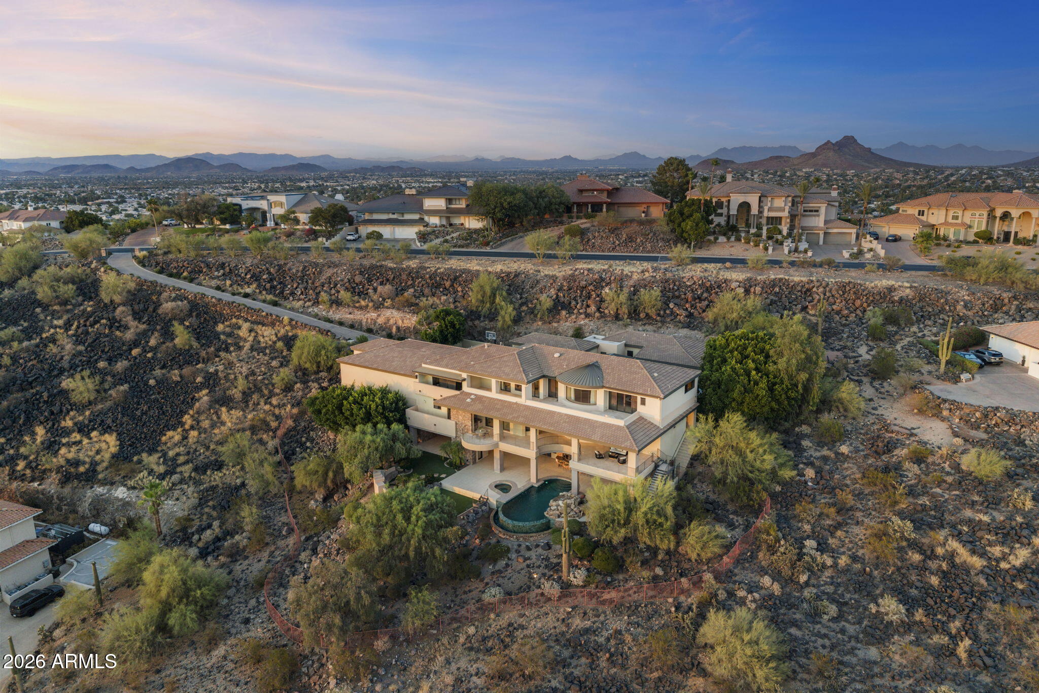 Experience architectural brilliance in the heart of Moon Valley, where panoramic mountain and sunset vistas stretch across the valley from atop one of Lookout Mountain's most coveted homesites. Located within exclusive guard-gated community of Coral Gables Estates, this estate spans 9,241 SF on 2.3 acres and represents a rare fusion of visionary architecture and commercial-grade construction. Designed by renowned architect Bob Bacon and constructed by Kitchell, Arizona's premier commercial builder, the residence showcases a level of craftsmanship, engineering, and design rarely found in residential real estate. The property is positioned to maximize indoor-outdoor living and includes an 888 SF detached guest house and garage space for up to 10 vehicles, including a detached RV garage. Designed for both grand-scale entertaining and everyday living, the chef's kitchen features striking River Green granite, a butler's pantry, an 18-chair island, abundant preparation space, and a fully retractable glass sliding door for an indoor-outdoor flow. An elevator provides convenient access throughout the home, while a commercial-grade Crestron smart home system seamlessly controls lighting, climate, audio, and integrated home functions.

The upper level hosts the primary retreat with a private study, guest bedrooms, conditioned storage, expansive patios, and a gas fireplace overlooking the surrounding landscape. The lower level serves as an entertainment retreat with a media/game room, full bar, guest suites, dual wine cellars, retractable bar windows, and fully opening slider doors for direct access to outdoor living spaces.

Outside, the resort-style pool and spa, dramatic grotto, vanishing-negative edge water feature and waterfall, and expansive patios create a private desert oasis designed to capture ever-changing desert light, dramatic sunsets, and star-filled skies. Located moments from Lookout Mountain Golf Club and surrounded by the natural beauty of the mountain preserve, this is one of Moon Valley's most significant legacy estates.