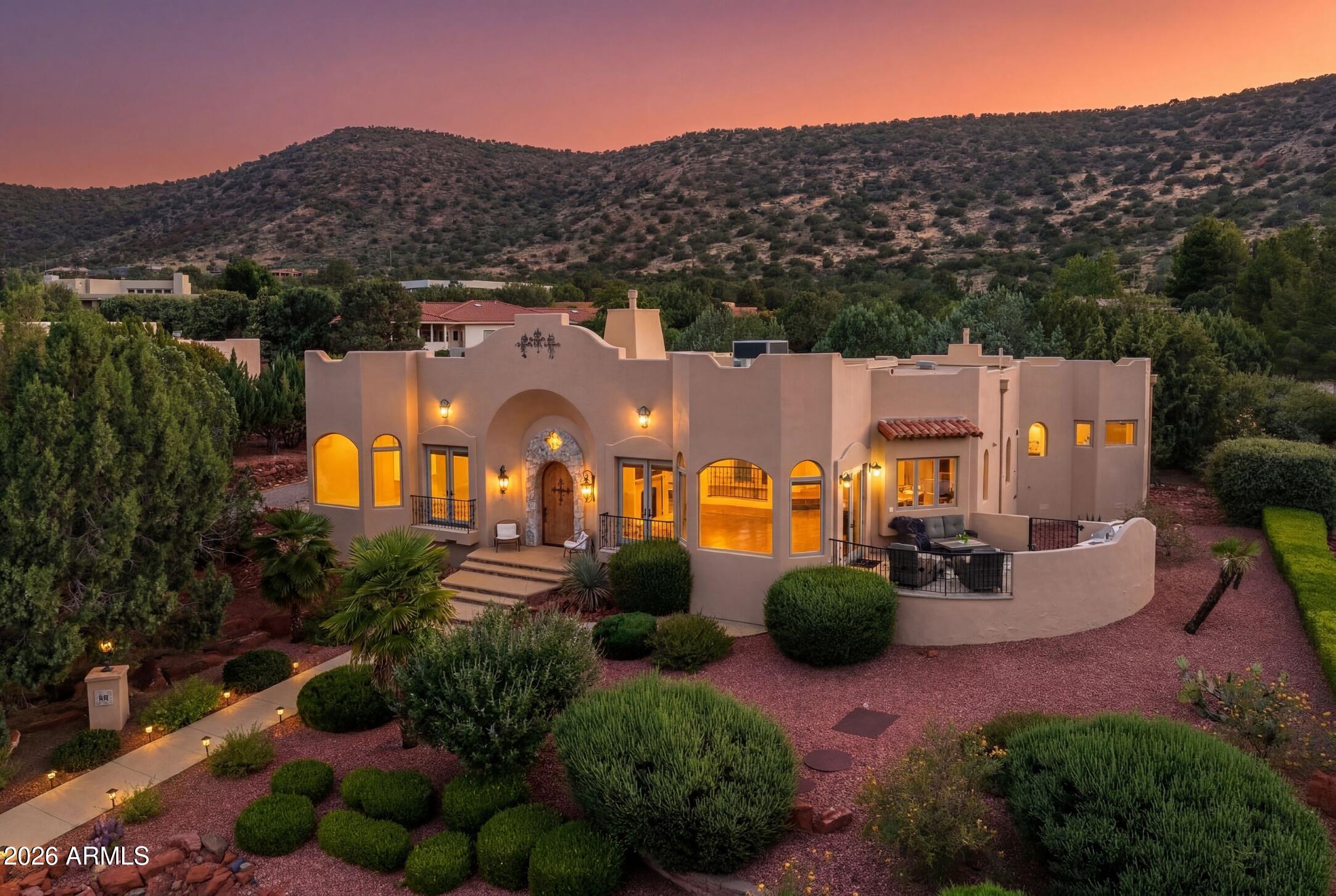 Your own private European escape--without leaving Sedona. Inspired by the timeless elegance of Mediterranean Revival architecture, this exceptional 3 BD + Office | 2.5 BA | 3 Car Garage | 3,870 SF estate is a celebration of romance. Graceful arches, sunlit interiors, and expansive windows capture old-world charm while framing red rock vistas. A secluded courtyard with a tranquil fountain evokes visions of Mediterranean enclaves inspired by Antibes, Venice, and the French Riviera. The courtyard offers space for vibrant bougainvillea and garden gatherings, both intimate and grand. Situated on .84 acres, the property embraces privacy + serenity. With no HOA, STR potential, a private wine grotto, + parking for 10, this extraordinary home blends old-world romance with Sedona's red rock majesty. Set at the base of the mesa within Sun Up Ranch, just steps from Coconino National Forest, this storybook estate invites you to slow down, savor the moment, and experience Sedona from an entirely different perspective. Arrive through a dramatic arched entry framed by handcrafted details. One need only pause beneath the ornate wrought-iron lighting surrounding the home and courtyard to appreciate the first expression of its sui generis charm and enduring old-world soul. Among the home's most captivating details is the decorative art-glass window above the front entry, which casts colorful prisms of light across the interior throughout the day. Reflections from the window are mirrored in the opposing glass, creating an ever-changing display of color and light that welcomes you home.

Gather with family and friends in two spacious living areas, anchored by a commanding gas fireplace and surrounded by graceful arches, artisan finishes, and architectural details rarely found in newer construction. The heart of the home is an impressive chef's kitchen designed for both everyday living and effortless entertaining, featuring furniture-quality custom alder cabinetry, a substantial center island, expansive natural stone surfaces, dual ovens, gas cooktop, and a generous walk-in pantry. Even ordinary moments become extraordinary when your kitchen sink overlooks a spectacular panorama of Castle Rock, Bell Rock, Courthouse Butte, and Sedona's iconic red rock skyline.

Take in those same awe-inspiring red rock views from the charming Juliet balcony off the living room, where sunrise paints the cliffs in luminous shades of gold and fiery sunsets linger long after dusk. Savor morning coffee on the spacious view terrace, host unforgettable dinners prepared on the built-in BBQ grill beneath Sedona's glowing evening skies, or simply relax with a glass of wine as the changing light dances across red rock cliffs and surrounding mesas. Beyond the main entertaining areas, a secluded seating retreat at the rear of the property provides a peaceful front-row seat to Sedona's natural beauty. Enjoy morning coffee while watching deer wander through the landscape, native birds gather nearby, and the occasional javelina pass quietly through the surrounding habitat.

Privately positioned on its own wing, the luxurious primary suite feels worlds away from the everyday, featuring its own gas fireplace, spacious walk-in closet, and beautifully appointed stone-accented bath with an oversized soaking tub and walk-in shower. French doors provide direct access to the secluded courtyard, creating a tranquil indoor-outdoor sanctuary. On the opposite wing of the home, two generously sized guest bedrooms share a well-appointed guest bath, while an expansive office with a private exterior entrance offers flexibility for remote work, creative pursuits, or a private studio. A dedicated laundry room and oversized three-car garage complete the home, with built-in workbench, extensive shelving, and abundant storage.

Descend through a private entrance to the enchanting wine grotto, an intimate retreat reminiscent of a centuries-old European cellar. A recessed 120-bottle cave à vin chills and preserves your precious vintages. Whether sharing a favorite bottle with friends or enjoying a quiet evening for two, this unique space adds a level of character and intrigue rarely found.

Completed in 2002 by a master builder whose clientele has included celebrities, executives, and royalty, the home showcases exceptional craftsmanship throughout. Curved walls, custom ironwork, carved alder doors, designer lighting, artistic finishes, marble, granite, and rich wood flooring reflect a commitment to quality at every turn.

With no HOA and short-term rental eligibility, the property offers remarkable flexibility as a luxury primary residence, lock-and-leave second home, or coveted income-producing retreat. Rich in character, timeless in design, and surrounded by some of Sedona's most iconic scenery, this is more than a home--it is an opportunity to experience old-world elegance in one of Arizona's most romantic settings.