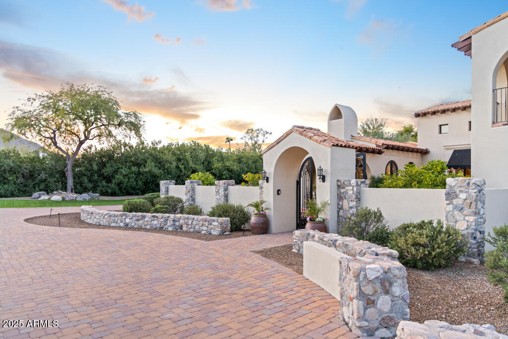 Set on 1.3 acres, this exceptional Spanish-style estate captures sweeping, unobstructed views of Mummy Mountain, the McDowell Mountains, and the Phoenix Mountain Preserve. A timeless architectural aesthetic is enhanced by hand-laid Mexican tile, rich hardwood floors, and warm marble countertops throughout the home.
The chef's kitchen is a showpiece, boasting a brand-new Viking appliance suite, an expansive center island with seating, and seamless connection to the surrounding living spaces—perfect for both daily living and entertaining. Each bathroom has been thoughtfully renovated with luxurious, high-end fixtures and finishes. Custom ironwork, including lighting, gates, and railings, adds artisanal character and speaks to the home's bespoke craftsmanship. An elegant staircase leads to the private primary retreat, complete with multiple balconies, a spacious sitting area, and panoramic views in every direction. The spa-like dual bathroom, generous walk-in closet, and serene ambiance create a true sanctuary. On the main level, two additional en-suite bedrooms offer comfort and privacy, along with a third bedroom currently utilized as an office.
The impressive lower level expands the living space even further, featuring a potential additional bedroom, a full bathroom with steam shower, a dedicated gym, and a private home theaterideal for relaxation or recreation. Guests will appreciate the separate casita, accessed from the exterior, providing total privacy and comfort.
Outdoor living is nothing short of spectacular. Hacienda-style patios wrap around manicured turf and overlook a striking Pebble Tec pool with custom tile detailing and a tranquil water feature. A surrounding fieldstone wall enhances both beauty and security, while multiple natural gas fireplaces create inviting spaces for evening gatherings.
Designed for refined living and effortless entertaining, this private compound offers an extraordinary lifestyle in a truly breathtaking setting. A rare opportunitythis remarkable estate must be experienced to be fully appreciated.