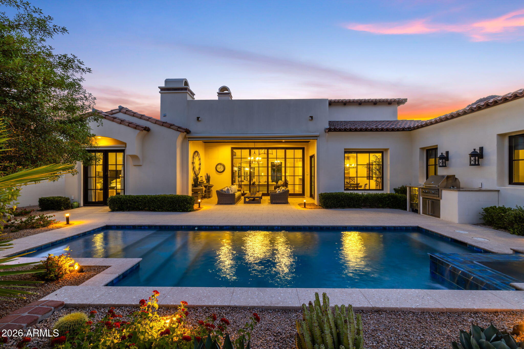 Tucked into one of Paradise Valley's most intimate and distinctive guard-gated mountainside communities, this home offers the rare combination of privacy, ease, views, and lock-and-leave luxury. Set against a dramatic mountain backdrop with city lights and desert views, this single-level residence lives beautifully with no interior stairs, generous indoor-outdoor flow, and a floor plan designed for both everyday comfort and effortless entertaining.

The main home features a warm architectural character, soaring ceilings, expansive living spaces, and a seamless connection to the resort-style backyard. Automated Wall of glass opens to the pool, spa, covered patio, and outdoor living areas, creating a private desert retreat framed by lush landscaping and mountain scenery. A rooftop patio captures elevated views of the surrounding hillside, city lights, and iconic Paradise Valley setting.

A detached casita adds exceptional flexibility for guests, extended stays, a private office, studio, or wellness space. The casita includes an attached, temperature-controlled single-car garage, complementing the home's three additional garage spaces. A long private driveway provides rare extra parking, ideal for guests or multiple vehicles without compromising the home's quiet, tucked-away feel.

Located in a small, private, guard-gated enclave at the base of the mountain, this residence offers a level of exclusivity rarely found in Paradise Valley: refined single-level living, meaningful garage capacity, guest-ready casita accommodations, and a rooftop view experience, all within minutes of Scottsdale, Paradise Valley resorts, dining, shopping, and world-class amenities.