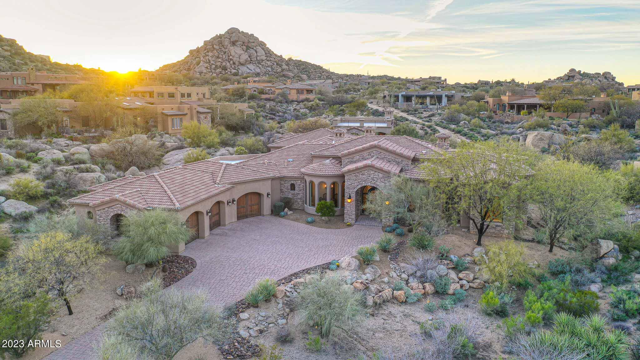 This luxurious custom home is nestled in the gated Pinnacle Canyon (Tierra Encantada) community at Troon North, offering unparalleled panoramic views of the breathtaking surroundings. Enjoy stunning vistas of boulders, Four Peaks, Tom's Thumb, Troon Mountain and McDowell Mountains from the spacious rooftop deck, complete with a cozy fireplace for warm and inviting evenings under the stars. This expansive property boasts a total of 6 bedrooms, with 4 located in the main home and 2 in the detached guest house. There are no interior steps inside the home or guest house. Each bedroom features its own private ensuite, ensuring ultimate comfort and privacy for all occupants. The property also features a private office located off the formal entry, offering a quiet retreat w/ stunning views. At 6,510 square feet, this home offers an exceptional living experience, complete with a wine cellar that holds over 500 bottles, perfect for entertaining guests or enjoying a quiet night in. The three-bay car garage features epoxy floors and ample storage space, with an extended paver driveway.

The exterior of the home is truly stunning, with smooth stucco and stacked stone accents that provide a timeless and elegant look. The exceptionally large covered patio is perfect for entertaining, featuring a built-in barbecue, tumbled travertine hardscape, and a cozy fireplace. The backyard is complete with a refreshing pool, fire pit, heated spa, and mature landscaping, making it the perfect oasis for relaxation and entertainment.

Inside, the great room features a dramatic water feature consisting of a natural boulder with a cascading waterfall, creating a serene and peaceful ambiance through the view window. Timeless interior finishes like Versailles pattern travertine, richly stained wood custom cabinetry, cantera stone accents, and smooth walls make this home truly special. 

The kitchen boasts granite counters, a 8-burner gas stove, center island with prep sink, secondary counter space for prep and an eat-in bar top, and Viking stainless steel appliances, including a Viking side by side fridge and freezer. The guest house also includes a kitchenette, perfect for accommodating guests or using as a separate living space.

Overall, this luxurious home in Pinnacle Canyon (Tierra Encantada) offers the ultimate living experience, complete with stunning views, exceptional amenities, and elegant finishes. Local fine dining, shopping, and numerous hiking and biking trails create the perfect community setting!