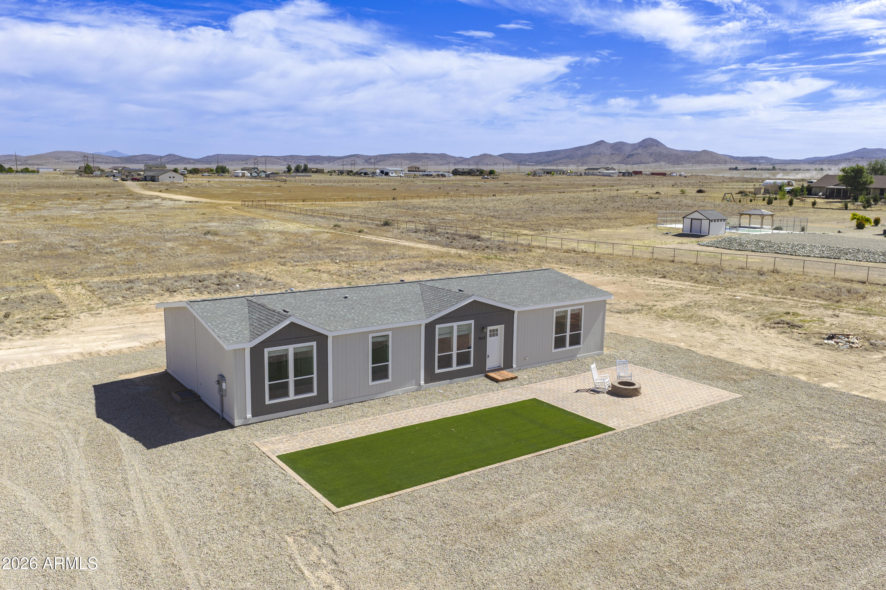 Brand-new energy-efficient home on 5 acres with breathtaking 360-degree views. Enjoy the perfect blend of rural privacy and convenient access to Prescott Valley amenities. Inside, a bright open-concept layout with 9-foot flat ceilings and massive picture windows creates a spacious atmosphere designed to showcase the surrounding mountain and desert vistas. Enjoy peaceful sunrises from the paver patio, evenings around the firepit, and the freedom of owning five fully usable acres with endless opportunities for horses, RVs, toys, and outdoor living. Highlights include: brand-new 2026 Clayton manufactured home, 1,980 square feet, 4 bedrooms, 2 bathrooms, E-Build energy-efficient construction, hard surface countertops, oversized walk-in pantry, luxury primary suite, glamour soaking tub, massive windows, private well producing approximately 12-15 gallons per minute, fully landscaped front yard, turf, rock driveway, paver patio with firepit, fenced property with sliding gate entrance, ample RV and toy parking, Clayton 1-year structural warranty. Experience the serenity of country living with wide-open skies, panoramic views, and room to spread out while remaining just minutes from shopping, dining, medical facilities, entertainment, and everyday conveniences in Prescott Valley.