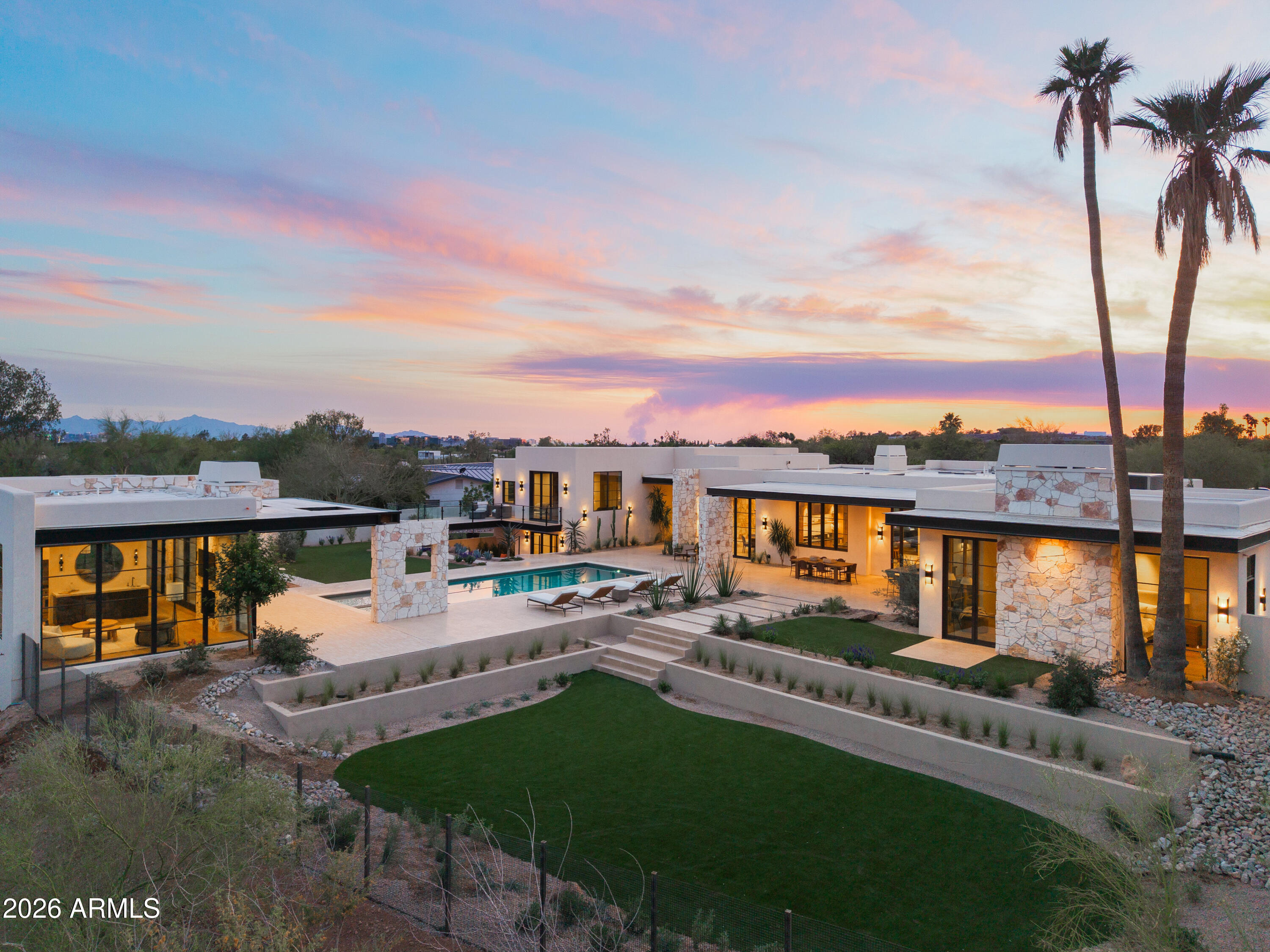 A masterful collaboration between two celebrated interior design studios and PHX Architecture, this warm modern estate is defined by intentional design, natural materiality, and elevated craftsmanship. Thoughtfully designed to harmonize architecture with landscape, the residence is anchored by hand-applied plaster finishes, expansive white oak detailing, and an extraordinary use of natural stone--each element selected for both beauty and longevity. Clean lines are softened by warm textures, while soaring 11-foot ceilings and 12 strategically placed skylights flood the home with natural light. A natural connection to the resort-caliber grounds creates an atmosphere that feels both refined and deeply inviting, designed for grand entertaining and quiet retreat. The floor plan is equally considered, offering a private owner's wing designed as a true sanctuary, intentionally set apart for privacy and quiet, with spa-inspired bath spaces finished in natural stone. The guest wing features two master-sized suites, each complete with its own living room--ideal for extended stays or multigenerational living. A dedicated wellness studio provides the perfect space for Pilates, yoga, or a private gym, further reinforcing the home's retreat-like sensibility.

Set on over an acre with full Camelback views, the over 9,000-square-foot estate offers a rare combination of scale, privacy, and architectural integrity, complete with a fully appointed guest house. Designed with walls of glass along a light-filled corridor, the guest house includes a private living room and full kitchen, creating an ideal environment for long-term guests, hosting, or independent living. From curated Ann Sacks stone and tile to custom millwork and luxury systems throughout, every detail reflects an uncompromising commitment to quality, resulting in a residence that is as enduring as it is exceptional.