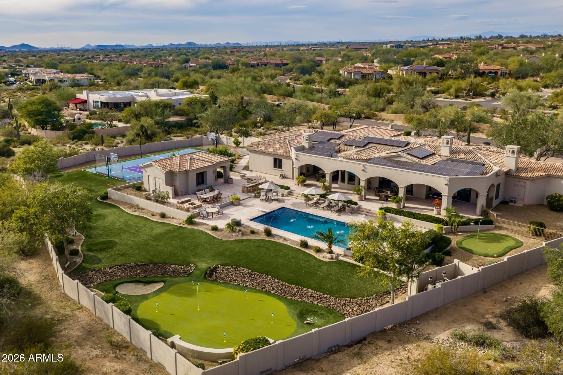 Situated on a sprawling 1.5-acre lot with sweeping and unobstructed mountain views and a sunny south-facing backyard, this fully reimagined North Scottsdale estate blends refined thoughtful design with true resort-style living. Mediterranean-inspired architecture and a circular paver stone driveway create a warm and inviting first impression.  Inside, the great room welcomes with a dramatic floor-to-ceiling granite fireplace and an expansive sliding glass door that pockets completely into the wall creating an effortless indoor-outdoor connection. Stunning limestone floors flow throughout the main living areas and are complemented by designer light fixtures and modern touches throughout. The chef's kitchen showcases Quartz countertops, sleek cabinetry, a generous island, and premium stainless-steel appliances including a built-in wine fridge and beverage drawers.  The primary suite is a true retreat, featuring a spacious bath with floating vanities, limestone flooring, and generous closet space. The guest wing offers 3 ensuite guest bedrooms, all connected to a large a bonus /media room that offers endless possibilities.  A dedicated office, additional bedroom, and a formal dining room complete the main home.  A detached casita serves as the 5th ensuite bedroom, ideal for guests, multigenerational living, or a private studio. Outdoors, the estate transforms into a private resort: two putting greens, a large sport court designed for both pickleball and basketball, a sparkling pool with deck jets, a raised spa with spillover, a built in BBQ, and a firepit create the perfect setting for outdoor gatherings against the stunning McDowell Mountain backdrop.  Multiple covered living and dining areas, including a deep covered patio with a cozy fireplace, encourage year-round enjoyment.  The property also includes owned solar and a 4-car garage with an electric vehicle charging station.  Tucked away yet conveniently situated within 5 minutes of the 101 Freeway and within a mile to DC Ranch's Market Street, the home offers a rare blend of serene surroundings and exceptional accessibility. This is Scottsdale living at its finestrefined modern finishes, remarkable views, exceptional outdoor amenities, and easy connectivity to everyday conveniences.