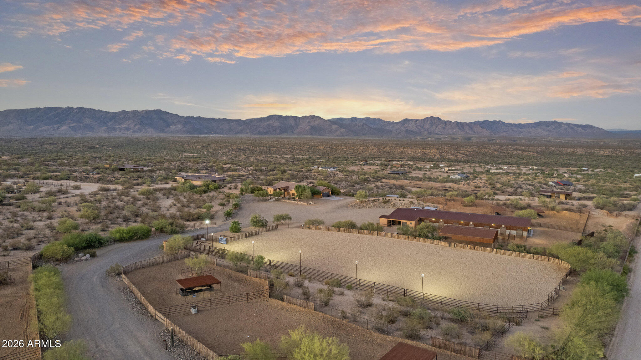 Gated 17.6-acre private equestrian ranch near Wickenburg with breathtaking mountain and desert views and no visible neighbors. This secluded luxury horse property is ideal for ropers, trainers, and show horse enthusiasts, offering a turnkey training facility and premier equine amenities. The 14-stall barn features 15x15 matted stalls with 15x20 runs, fans, heaters, equine performance lighting, and red light therapy. Two professional arenas include a 135x280 roping arena and ranch trail arena. Over 15 turnout pens provide ample space for horses and cattle. A highly rated well system supplies a 5,000-gallon holding tank with constant pressure pump. The 2018 custom home includes knotty alder cabinetry, gourmet gas range, and citrus grove. Bright interiors showcase unobstructed mountain views Room for multiple home sites and future expansion.