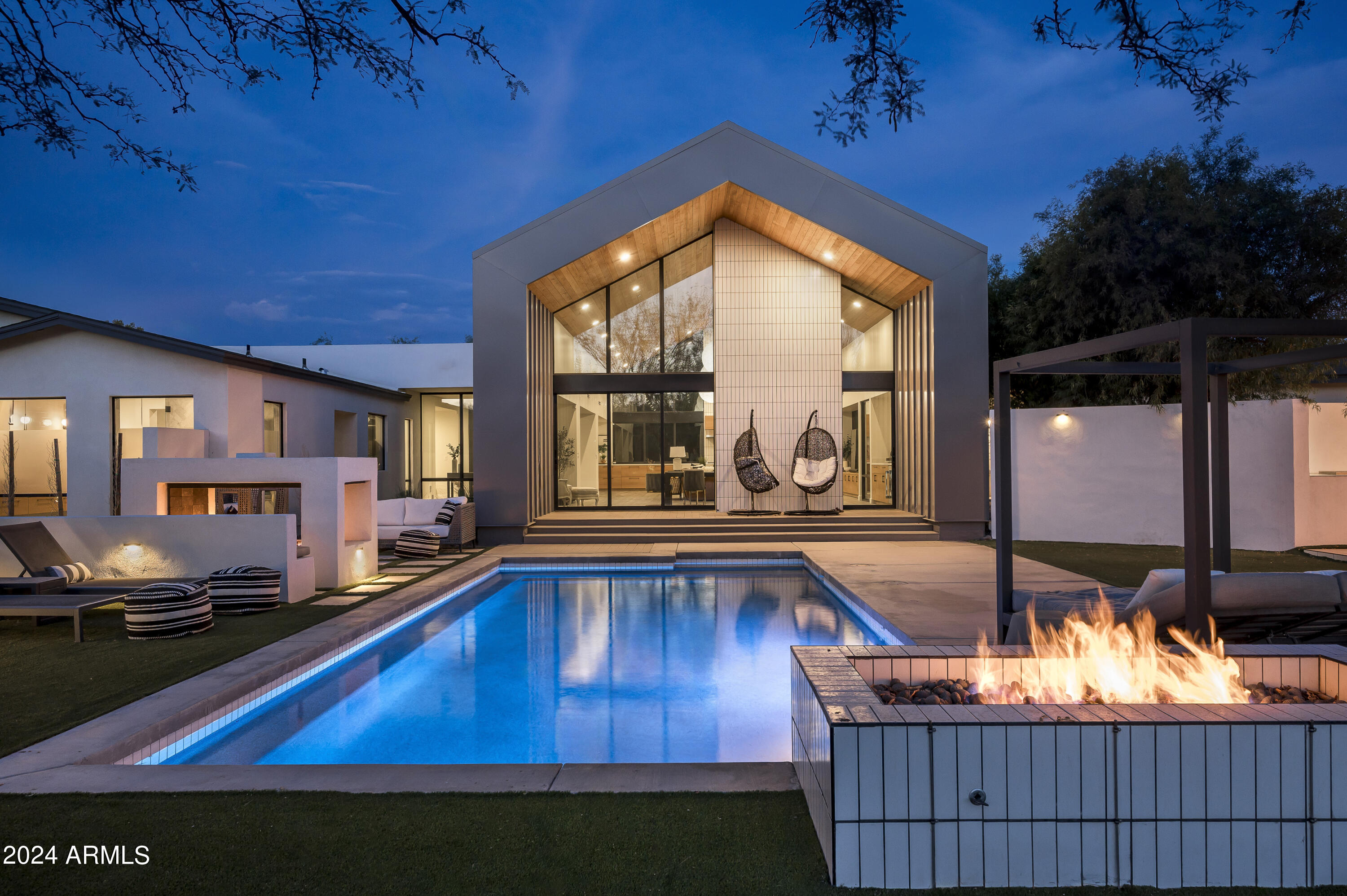 Step into a modern sanctuary at 11420 N Sundown Dr, an exquisite creation by Aperture Design. This contemporary marvel perfectly harmonizes natural elements with a spacious, airy design, offering a unique blend of luxury and tranquility. Set on over 1.5 acres that feels close to 2 with the way in opens up and all sits in the useable backyard, this estate is more than just a home—it's your own private retreat.

The backyard is an entertainer's dream, featuring premium, maintenance-free turf and a state-of-the-art three-zone misting system to keep you cool during the hottest days. Whether you're practicing your swing on the Par 2 chip and putting green, taking a dip in the stunning pool, or gathering around one of the multiple outdoor fireplaces, this space is designed for relaxation and entertainment.
The shaded outdoor living room, complete with a TV , and the
fully outfitted outdoor kitchen are perfect for both laid-back evenings and lively get-togethers. Sports enthusiasts will delight in the sand volleyball, pickleball, and basketball courts. Finished in late 2023, the comprehensive backyard renovation provides endless opportunities for enjoyment and peaceful relaxation.

Inside, 11420 N Sundown Dr continues to impress with its meticulous attention to detail, crafted for both luxurious living and entertaining. A grand glass pivot door welcomes you into an elegant foyer, setting the tone for the home's sophisticated ambiance. The main living area is defined by soaring 25-foot wood-covered ceilings and expansive sliding panel windows that seamlessly merge indoor and outdoor living. The gourmet kitchen, generous dining area, and expansive living space are ideal for everything from intimate family moments to grand celebrations.

The vast patios are the perfect spot to enjoy Arizona's breathtaking sunrises and sunsets. The back patio seamlessly connects to the pool, outdoor kitchen, and living room with fireplaces, making the most of this backyard paradise.

A short corridor leads to the oversized three-car garage, complete with ample storage and a full butler's pantry, featuring an extra refrigerator and sinkideal for enhancing your entertainment experience.

The residence wing, located opposite the entry foyer, ensures maximum privacy and comfort. It features dual master bedrooms in a split floorplan, each offering luxurious amenities. The primary master suite boasts a serene patio overlooking the backyard, an expansive walk-in closet, and a spa-like bathroom with a nine-sprayer shower and a deep soaking tub for two. The secondary master suite also includes a large walk-in closet, a soaking tub, a rain shower, and shares a generous patio with the gym/studio.