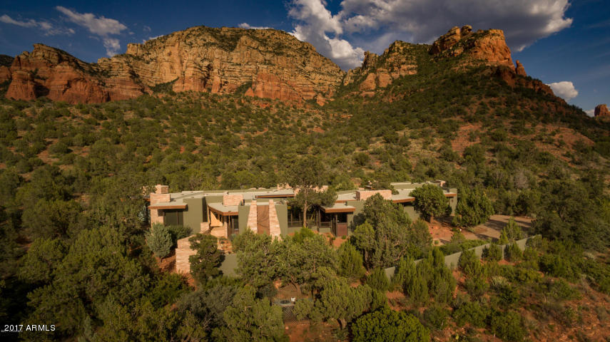 This Design Group contemporary masterpiece is truly an extraordinary residence. It’s the ultimate architectural work of art, drawing together extravagant elements of stone, glass, wood, metal, and water in a brilliant composition that exemplifies the best of its gorgeous U.S. National Forest setting – and, in turn, blends in with it organically. It’s a marvelously livable home that embraces you in luxurious comfort as well as beauty. It’s Sedona gracious living at its best, where the elegant interior flows seamlessly to the magnificent outdoors. Inside, the exquisite design of the living room, dining room, chef’s kitchen, exercise room, study, and master bedroom suite epitomizes quality beyond expectation, complemented by stunning red rock views from every window. An inner courtyard entices you to become one with nature while relaxing by the pool or enjoying a romantic alfresco dinner. On the far side of the courtyard your family and friends will delight in the spacious and beautifully appointed guest casita. On the northern side of the two and half acre lot, we find a 1,200+ sq.ft. studio/guest house with additional living quarters, expandable garage space, and a versatile studio. The entire property is surrounded by a privacy wall and fencing, with two custom metal entry gates to each garage. Inside, the compound feels like a world unto itself - quiet, serene, and bathed in beauty. Search as you might, you'll find no other home like it in Sedona: "This is the best house I've ever seen in Sedona." This comment from a veteran agent was enthusiastically echoed by the other members of the Sedona Luxury Real Estate Professionals present at a recent evaluative gathering at 1800 Dry Creek Road. This no exaggeration. Come experience this very special home. 

Features and Amenities 

Custom gated entry 
Paver and flagstone driveways, entries, and pathways 
Design Group Architects 
Sedona Custom Homes (John Griffin) Builder - who says. "This home has the most exquisite design features and ultra high-end quality components of any home I've seen in Sedona." 
"Smart home" capabilities with iPad 
Tom Aderhold custom front door and light fixtures/glass work 
Floor-to-ceiling windows 
Birdseye maple cabinets and doors by Traditional Craftsmen/Brian Smutz master woodworker 
AZ Flagstone and hardwood flooring 
Italian tile master bath 
Guest bath in West Wing has steam room. 
Kitchen: SubZero, Miele, Dacor 
Custom media room 
Private executive office 
Exercise studio room 
Custom water feature and stream in the Courtyard 
Accordion panel glass doors that open for great indoor-outdoor living 
Outdoor kitchen 
Studio can also be a full guest house or car collector garage 
Whole house Venmar air exchanger 
All fireplaces are versatile - that is they are plumbed for gas, but have masonry chimneys and can burn wood if desired.